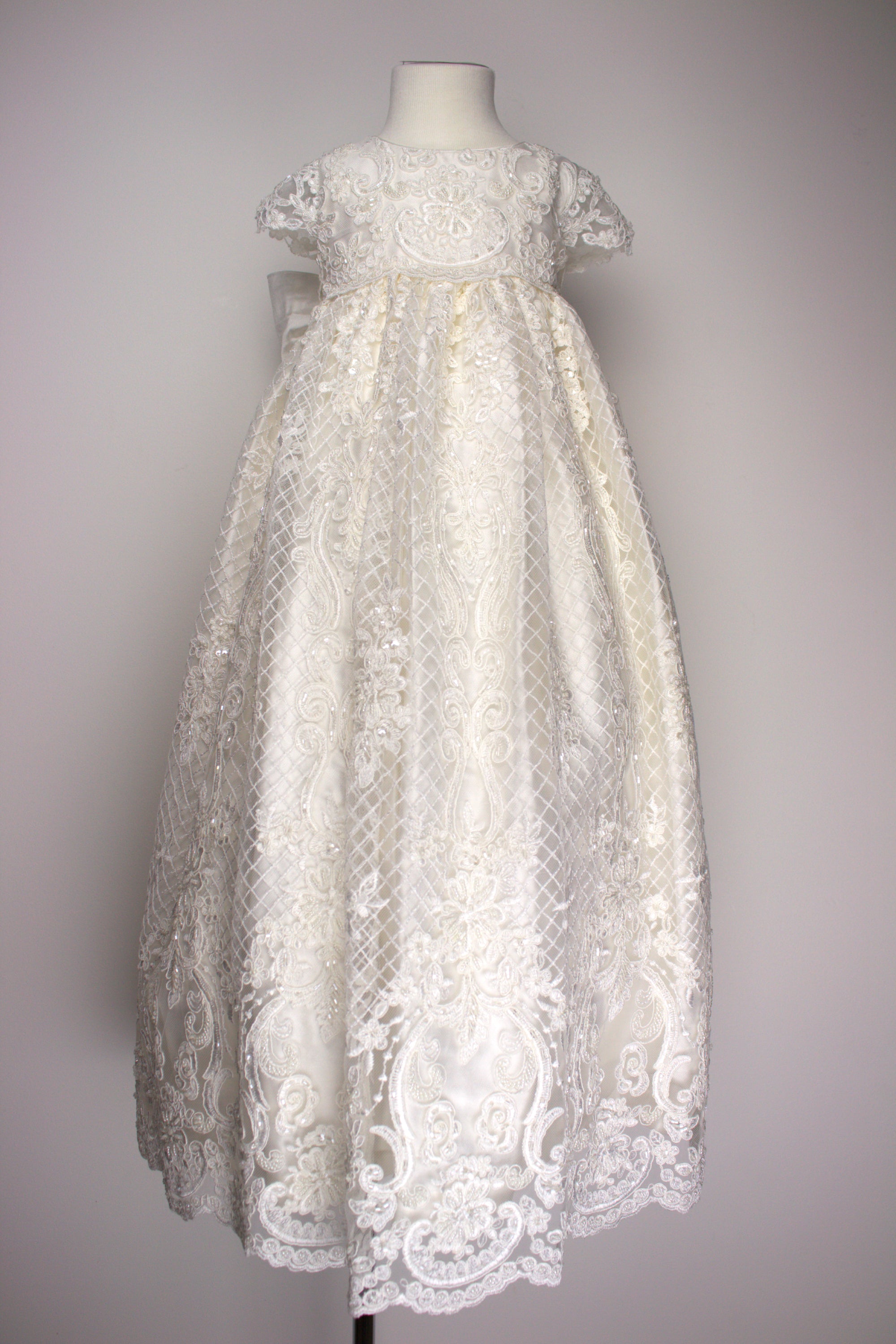My Blessing ivory christening gown from the Bithiah set featuring an embroidered lace bodice, elegant sleeves, and a flowing silk‑underlay skirt.