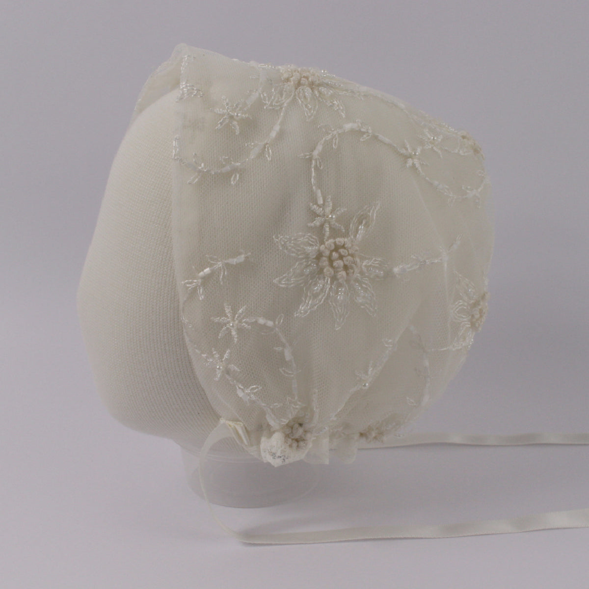 Ivory christening bonnet from the My Blessing Devotion set featuring European floral lace with delicate glass seed bead accents.