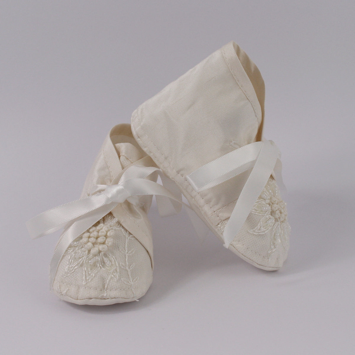 Ivory christening shoes from the My Blessing Devotion set featuring European lace with subtle glass seed bead detailing.