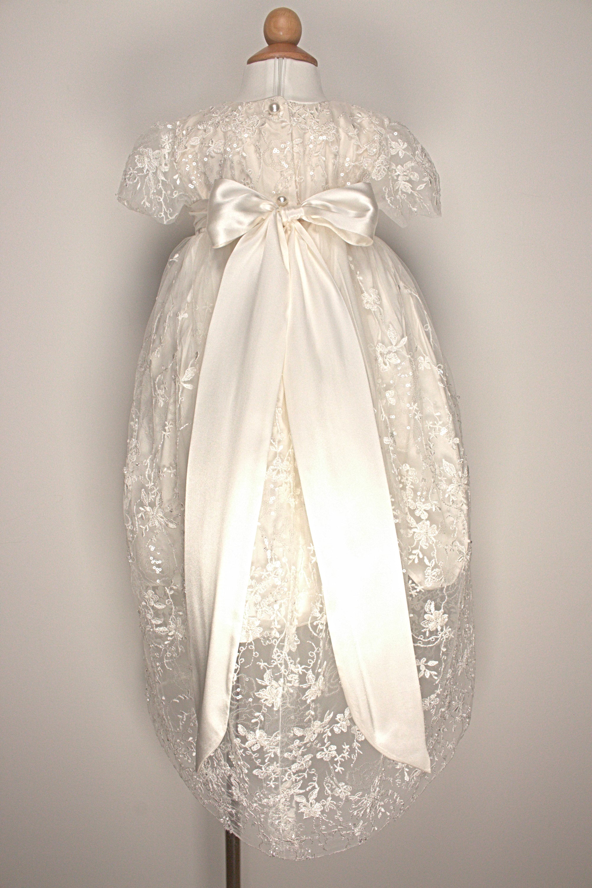Back view of the My Blessing Eternal ivory christening gown showing lace detailing, back closures, and the smooth satin skirt.