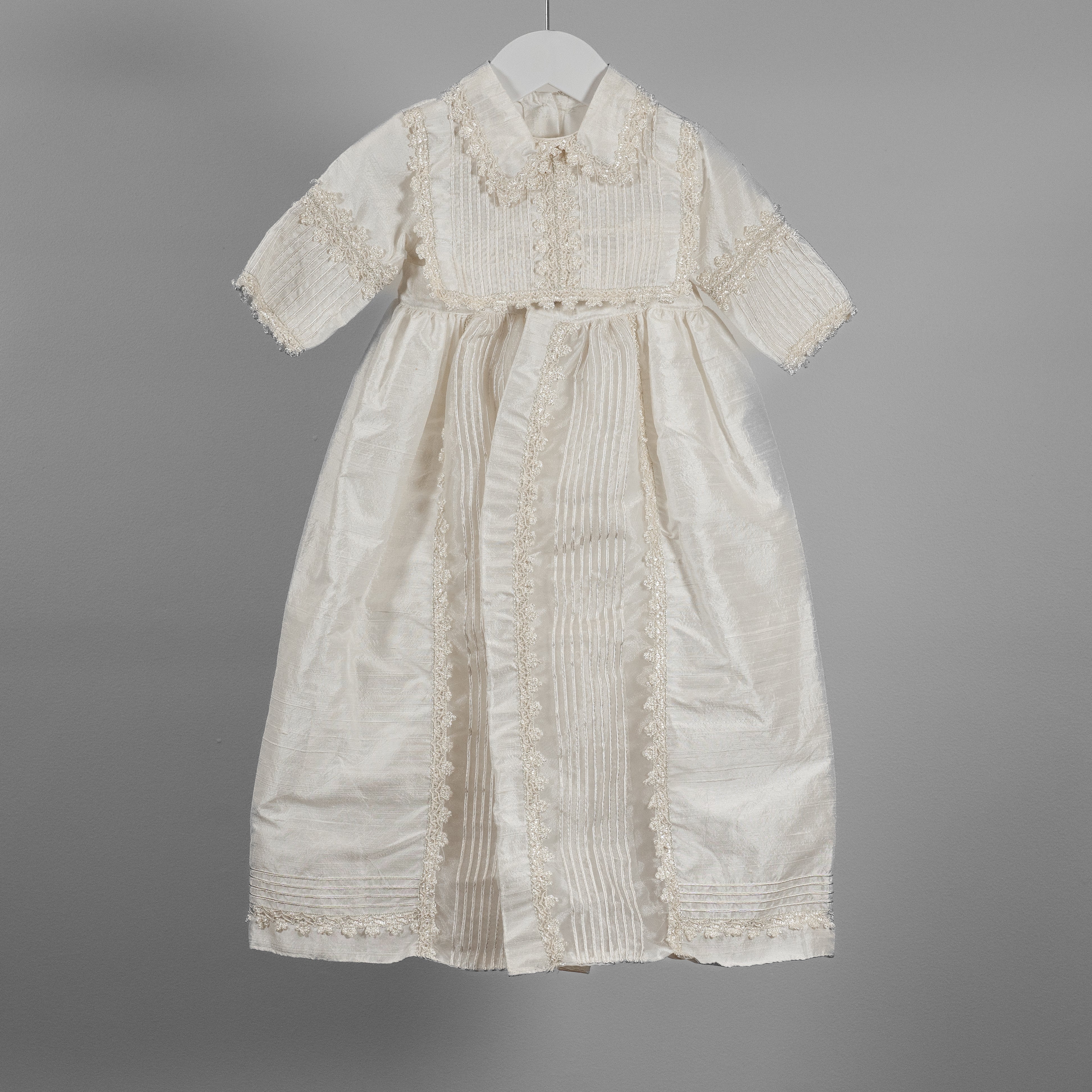 Front view of My Blessing ivory Ezra Dupioni silk baptism romper featuring a softly draped bib panel with elegant shuttle lace detailing.