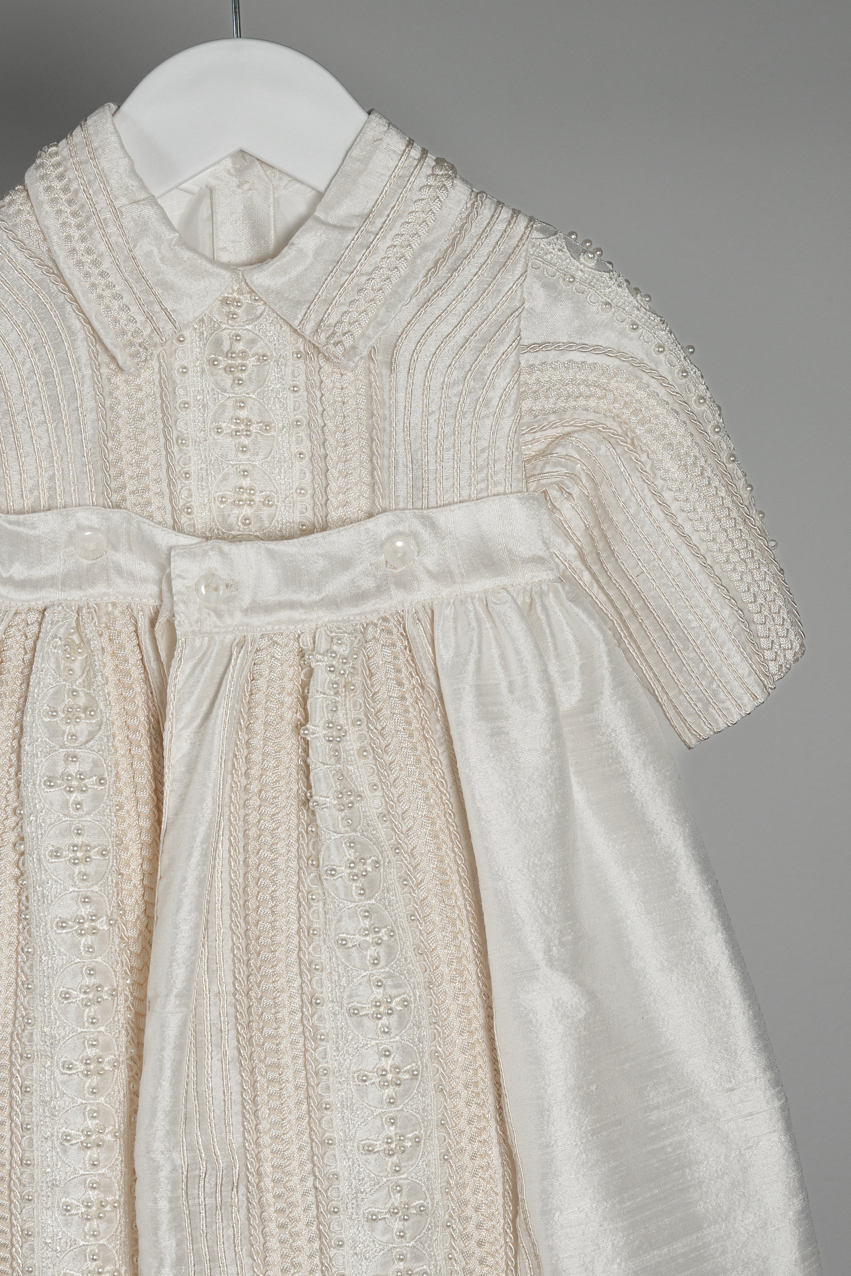 Close-up of the My Blessing Gabriel silk romper and detachable skirt showing miniature hand‑placed pearls and delicate woven lace accents.