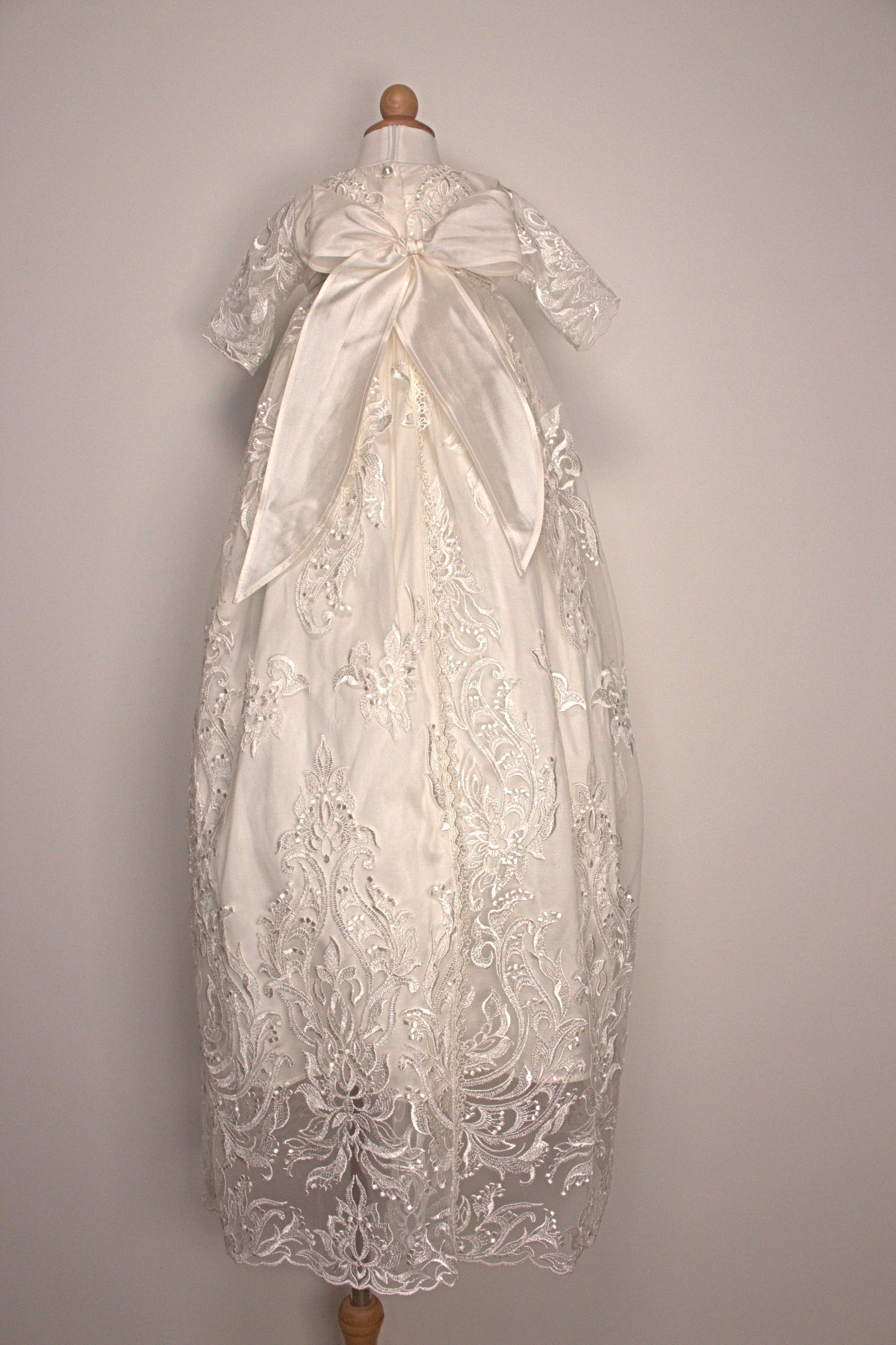 Back view of the My Blessing Glorious ivory christening gown showing lace detailing, back closures, and the smooth satin skirt.