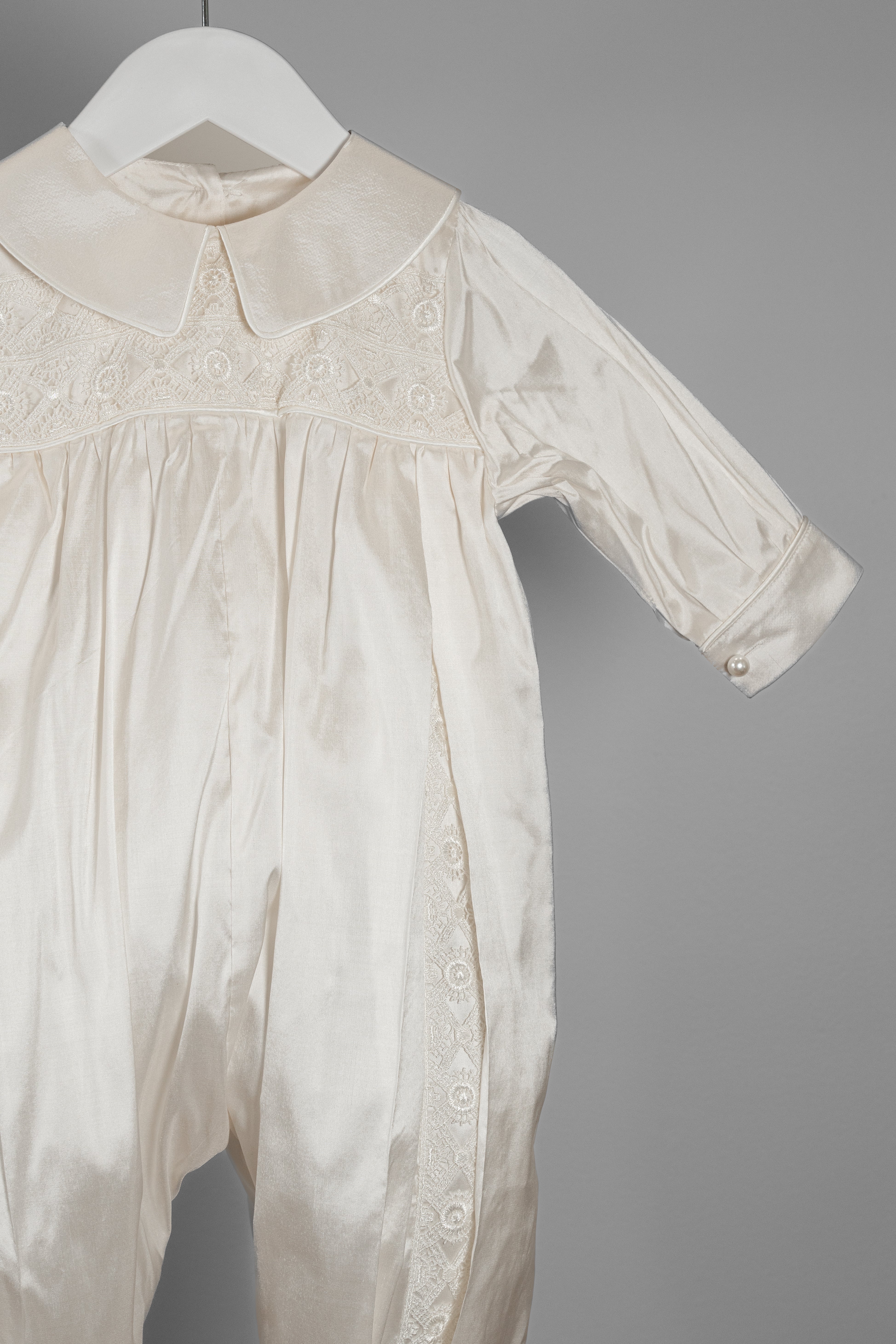 Macro shot of the My Blessing Lael romper’s Dupioni silk highlighting its natural texture and refined lace accents.