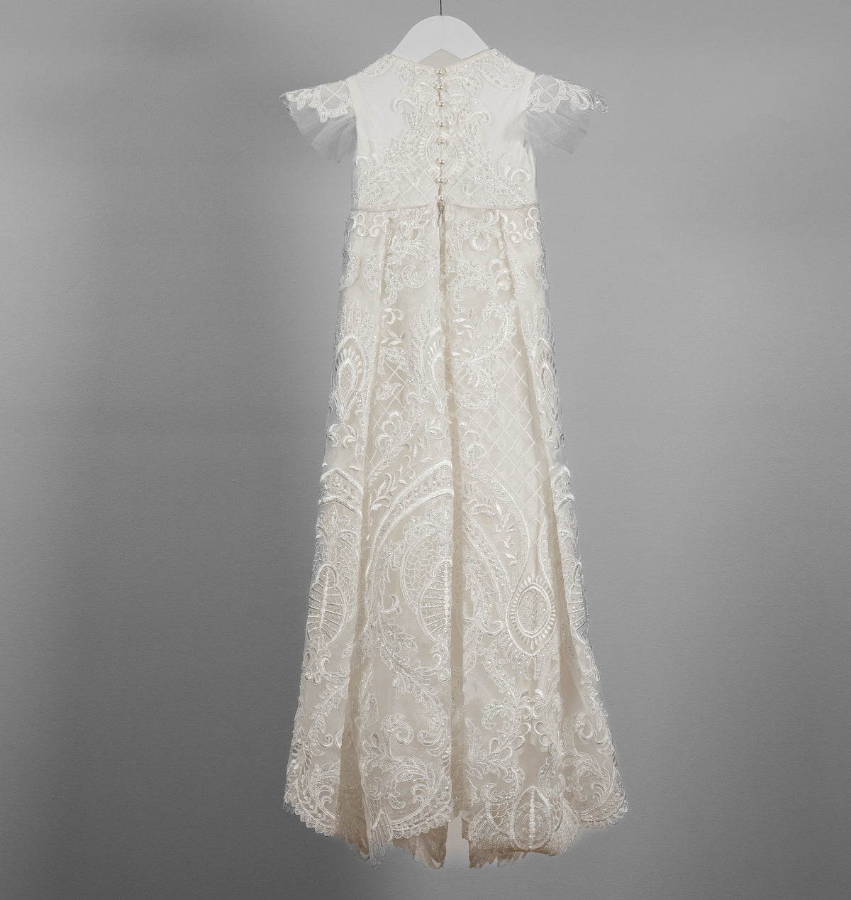 Back view of the My Blessing Lilly ivory christening gown showing lace detailing, back closures, and the soft cotton‑underlay skirt.