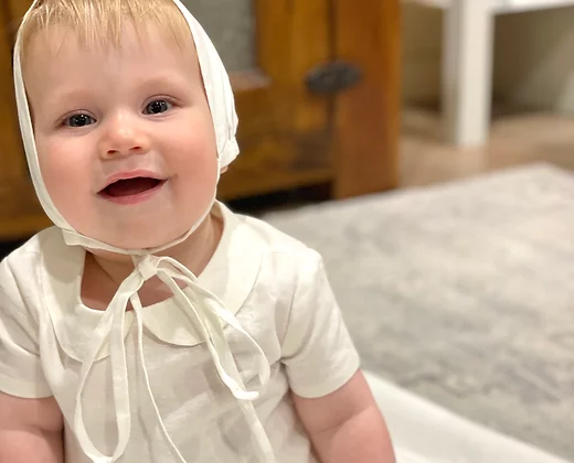Close up of baby boy wearing the My Blessing Noa gown showing the soft 100% cotton lining designed for all‑day comfort