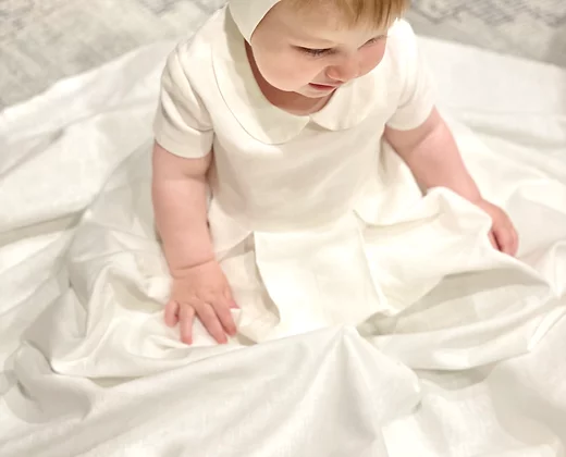 Close-up of baby boy wearing My Blessing Noa christening gown showing the linen texture, Peter Pan collar, and clean front pleat detailing.