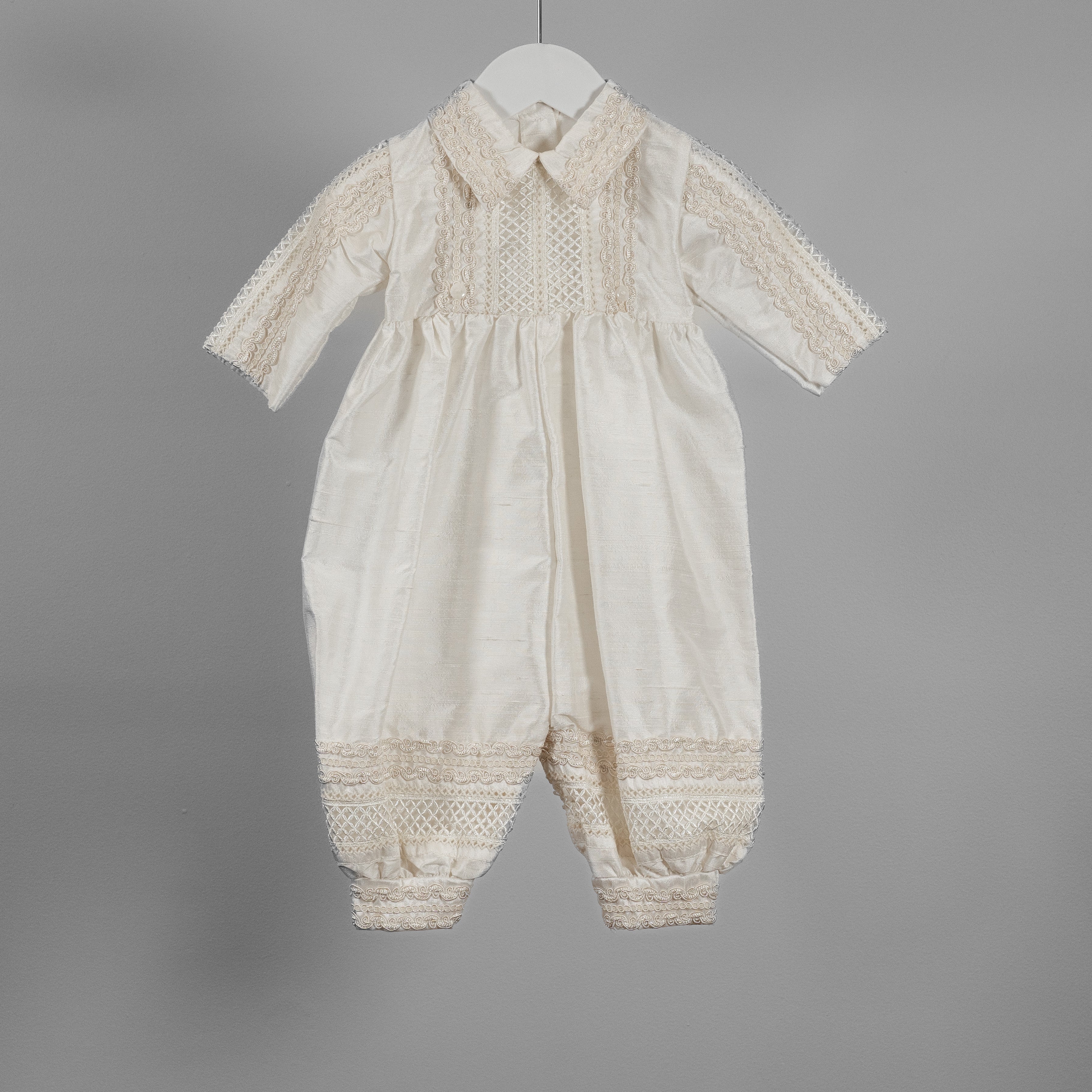 Close-up of the My Blessing Noah silk romper showing the delicate shuttle lace trimming along the chest and collar.