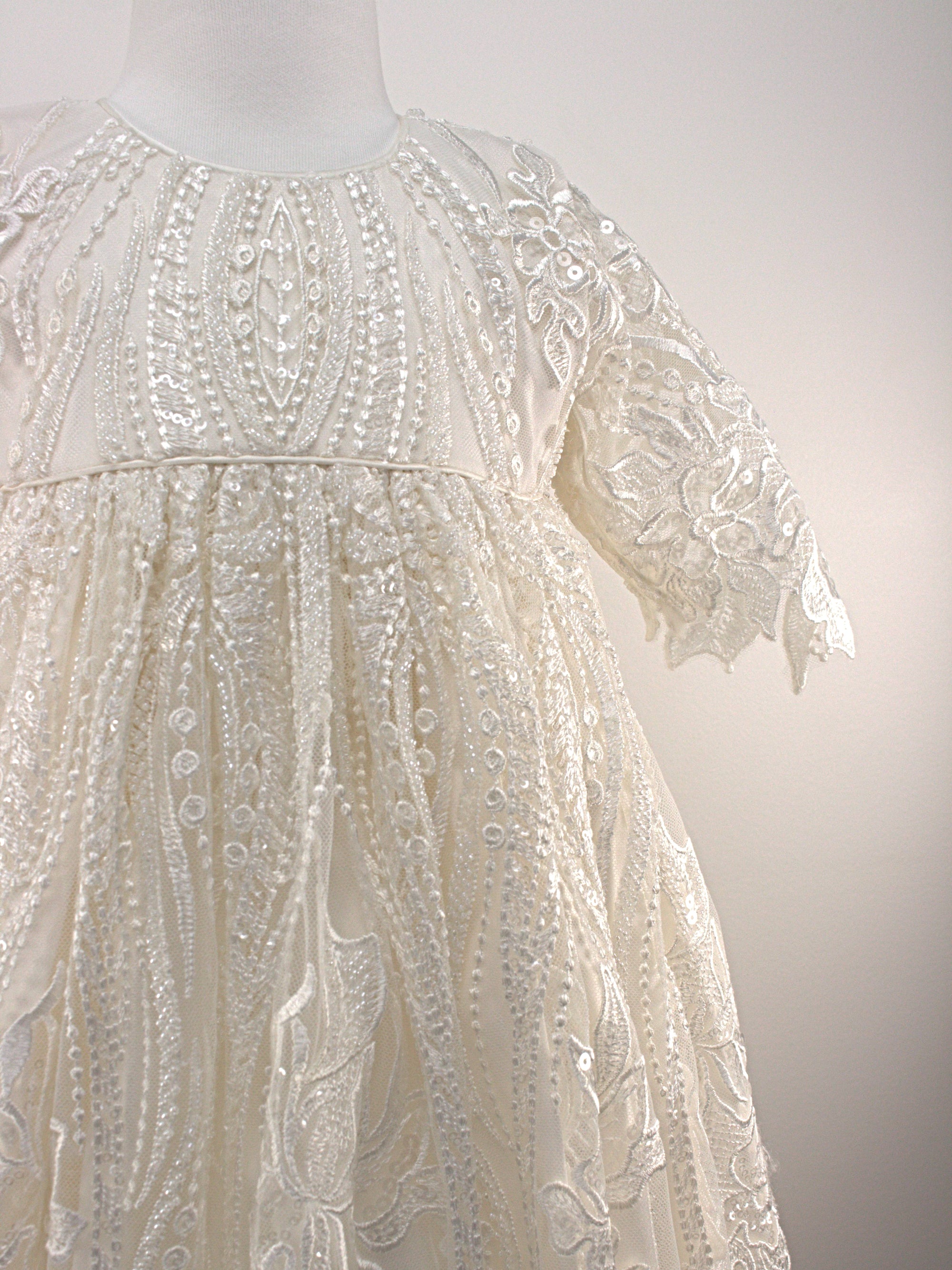 Close-up of the My Blessing Praise christening gown’s front bodice showing detailed floral lace and bead embroidery.
