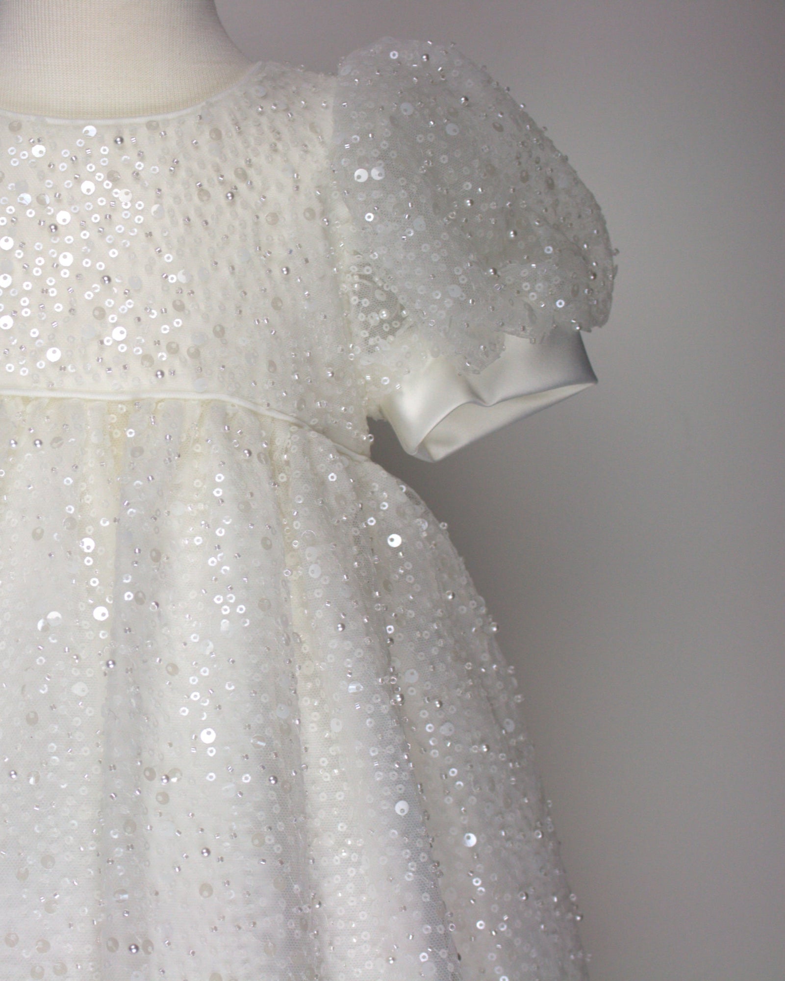 Close-up of the My Blessing Ruth christening dress’s front bodice showing intricate floral lace embroidery embellished with sequins, glass seed beads, and miniature pearls.