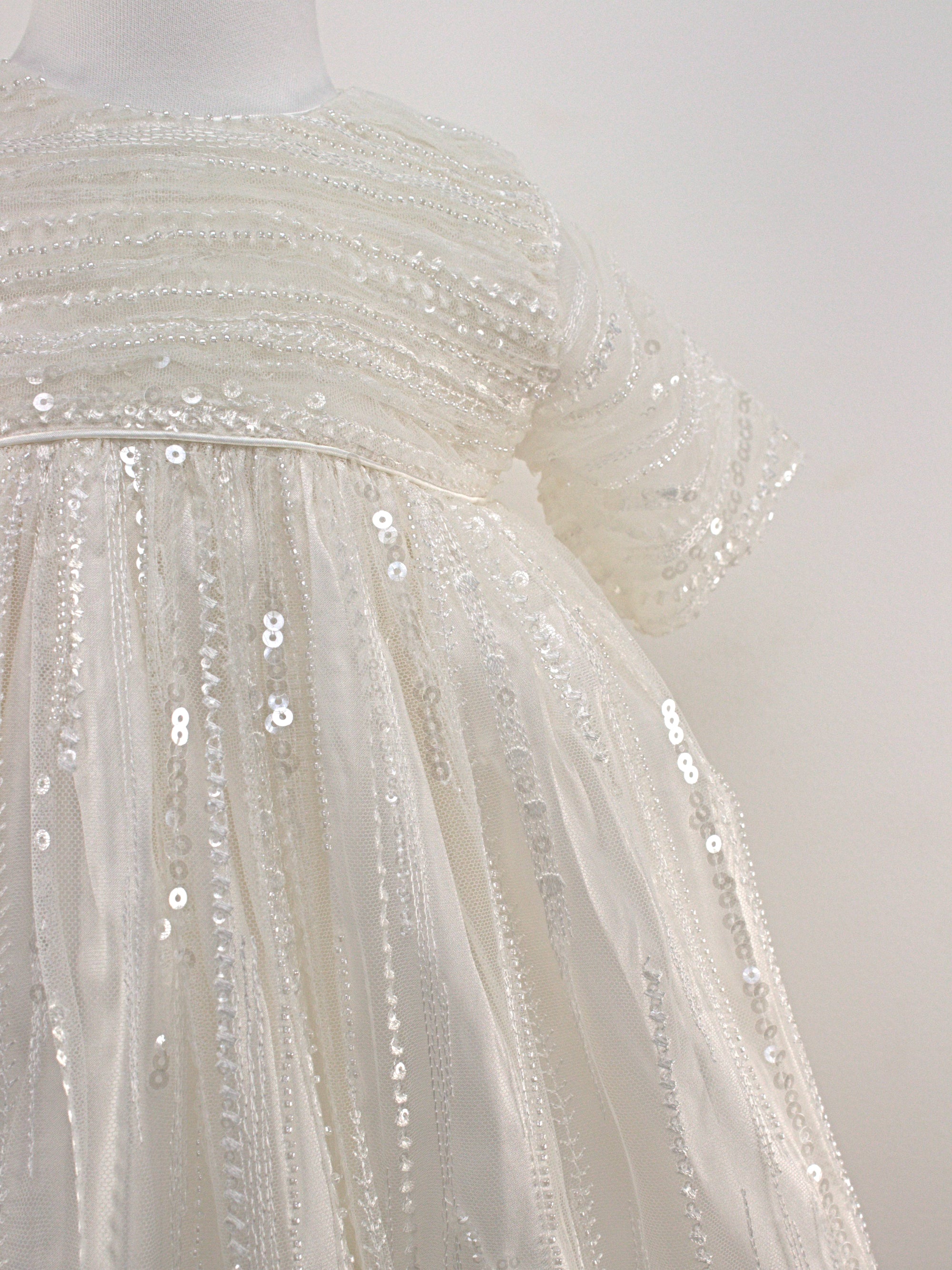 My Blessing Soul ivory christening gown from featuring an embroidered lace bodice, short sleeves, and a flowing satin skirt.