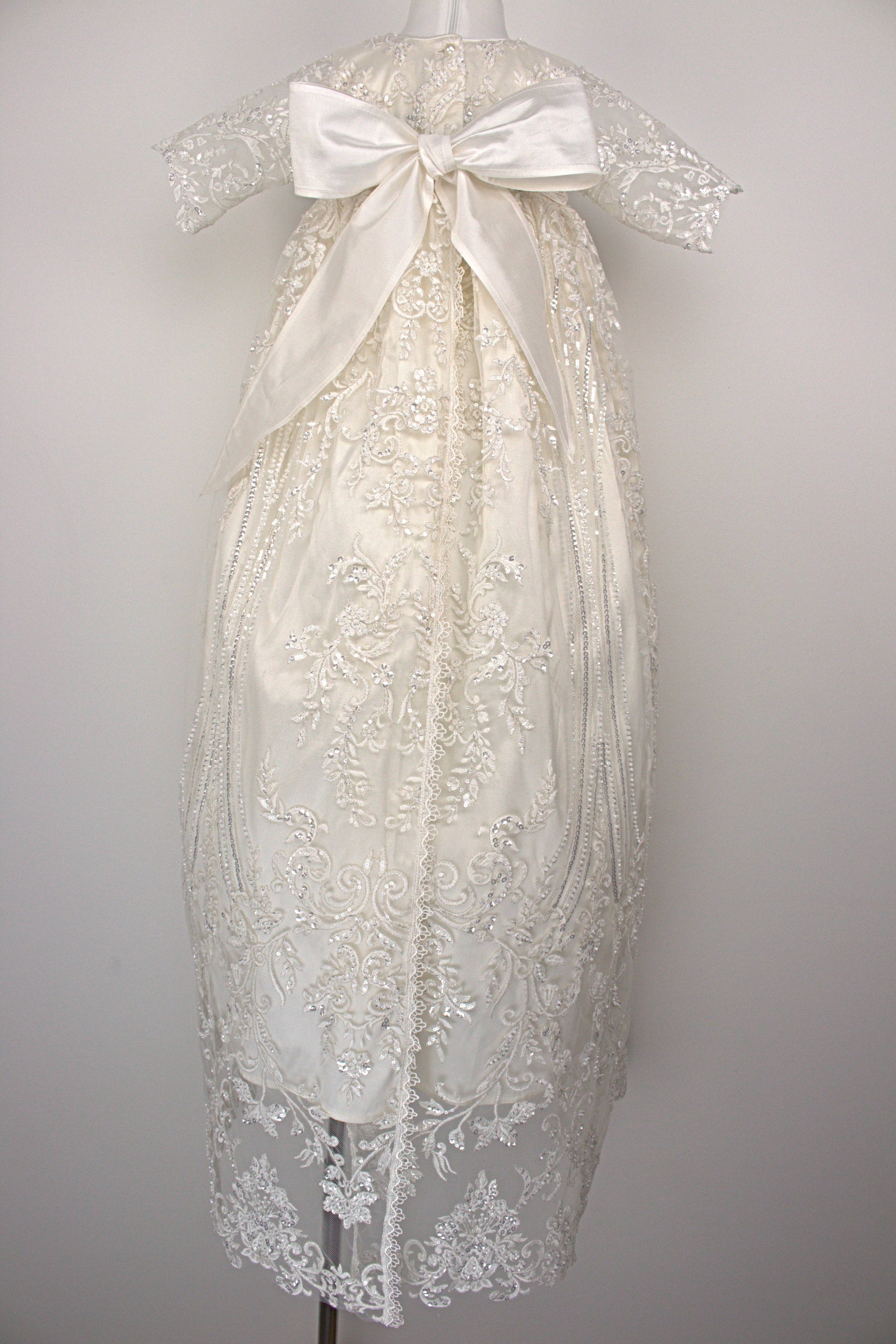 Back view of the My Blessing Wholesome ivory christening gown showing lace detailing, back closures, and the smooth satin skirt.
