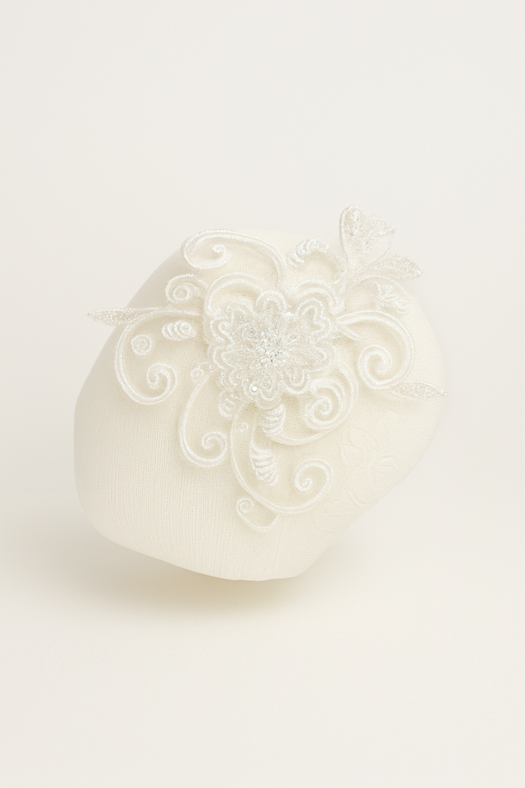 White y headband item with intricate patterns on a light beige background