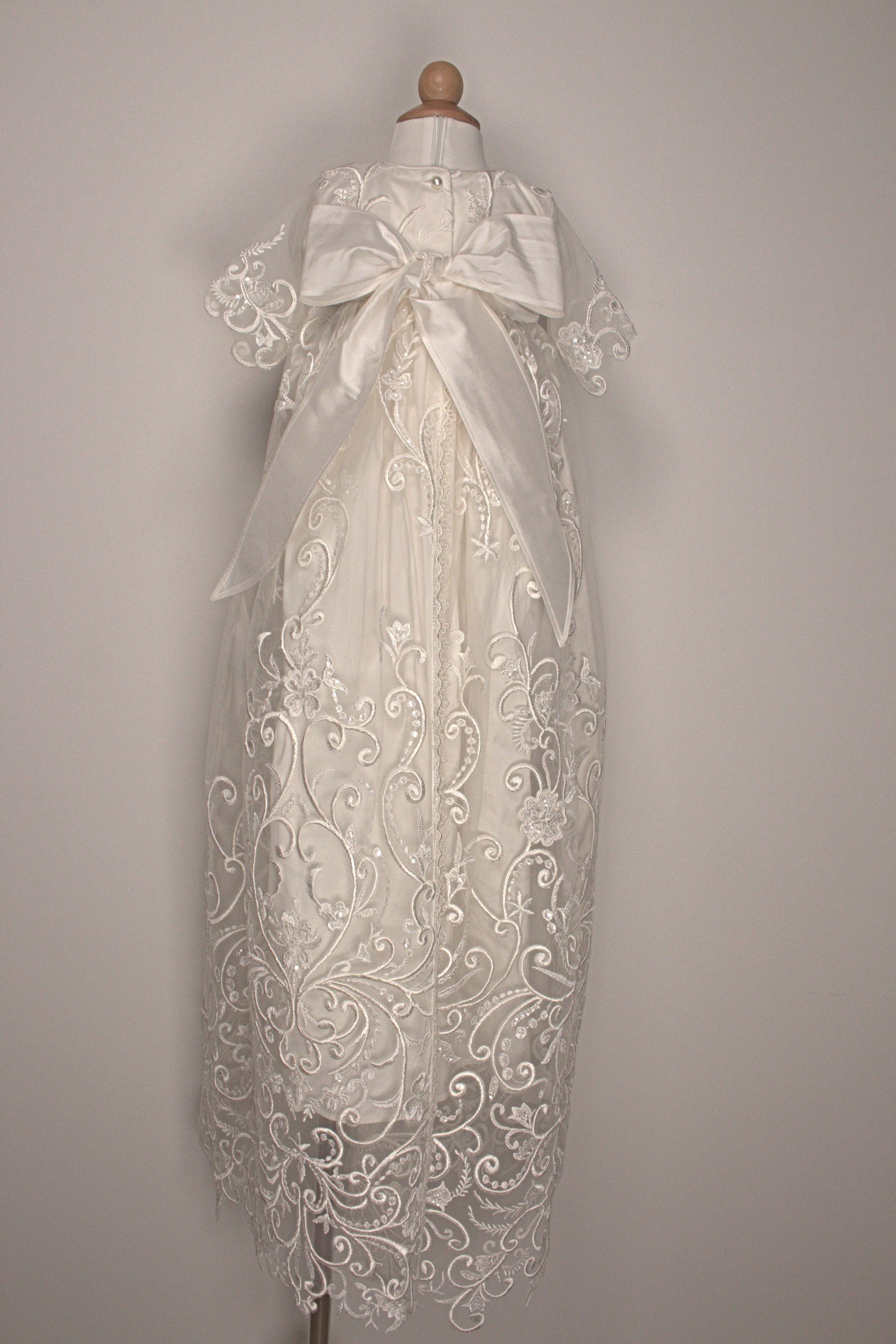 Back view of the My Blessing Calm ivory christening gown showing lace detailing, back closures, and the smooth satin skirt.