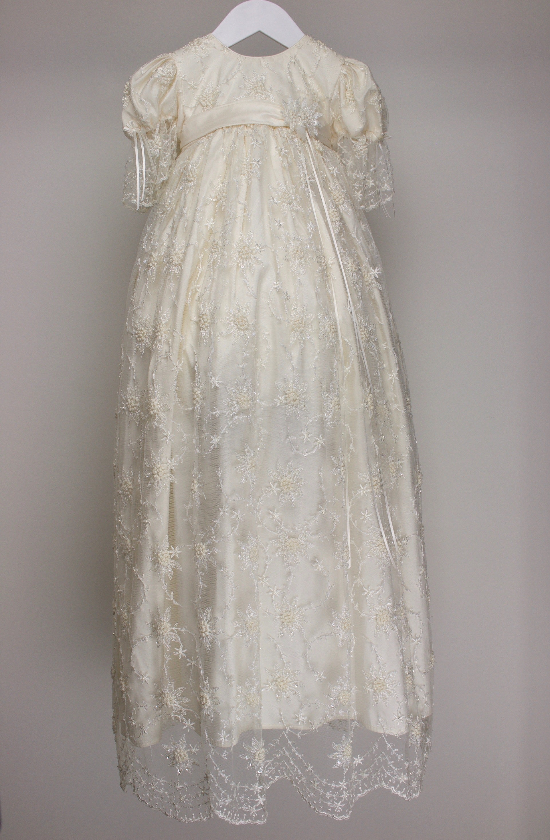 My Blessing ivory full‑length Devotion christening gown featuring a European floral lace overlay with delicate glass seed bead detailing
