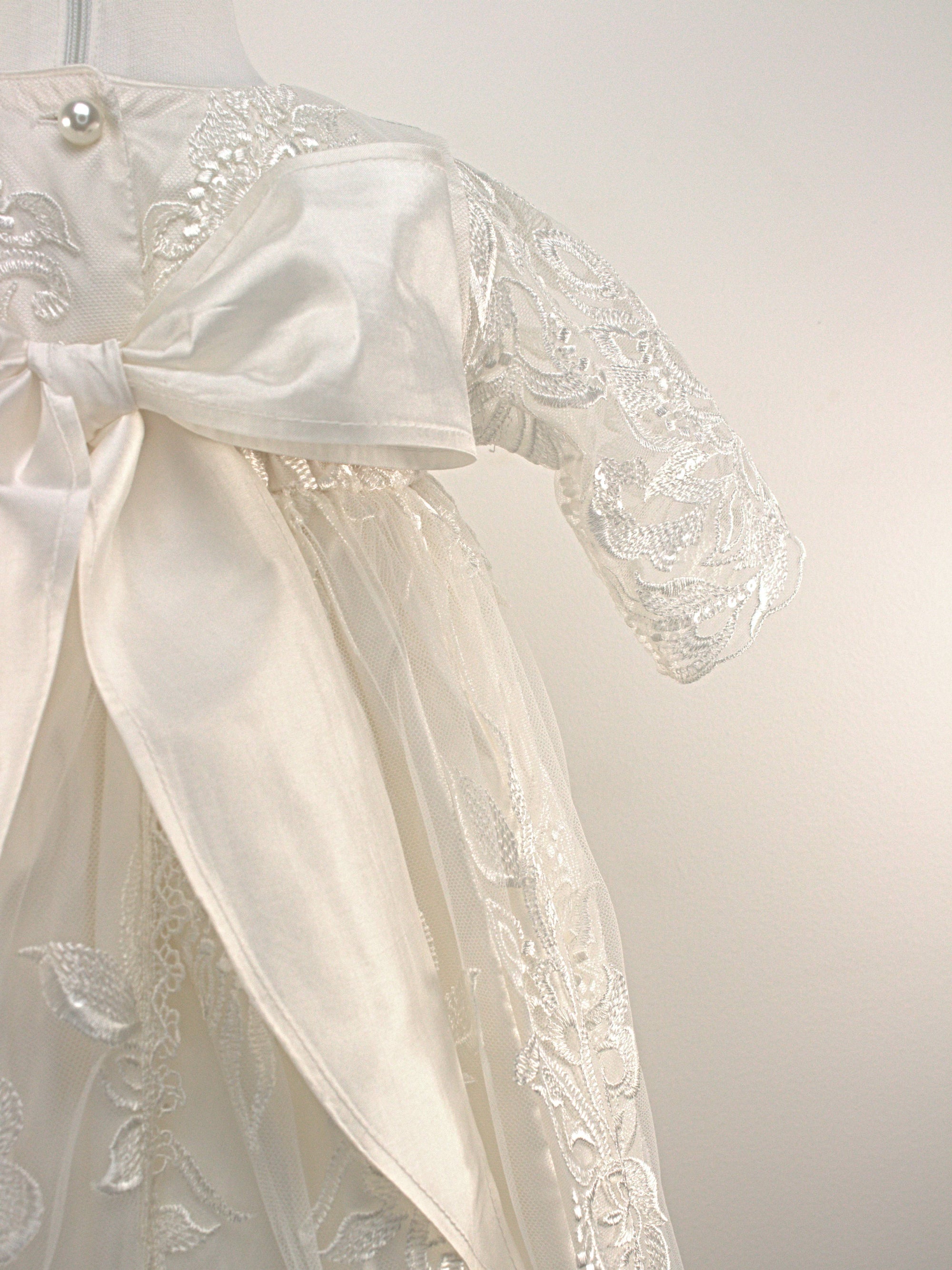 Close-up of the My Blessing Divine christening gown’s back bodice featuring delicate lace patterns and button or tie closures.