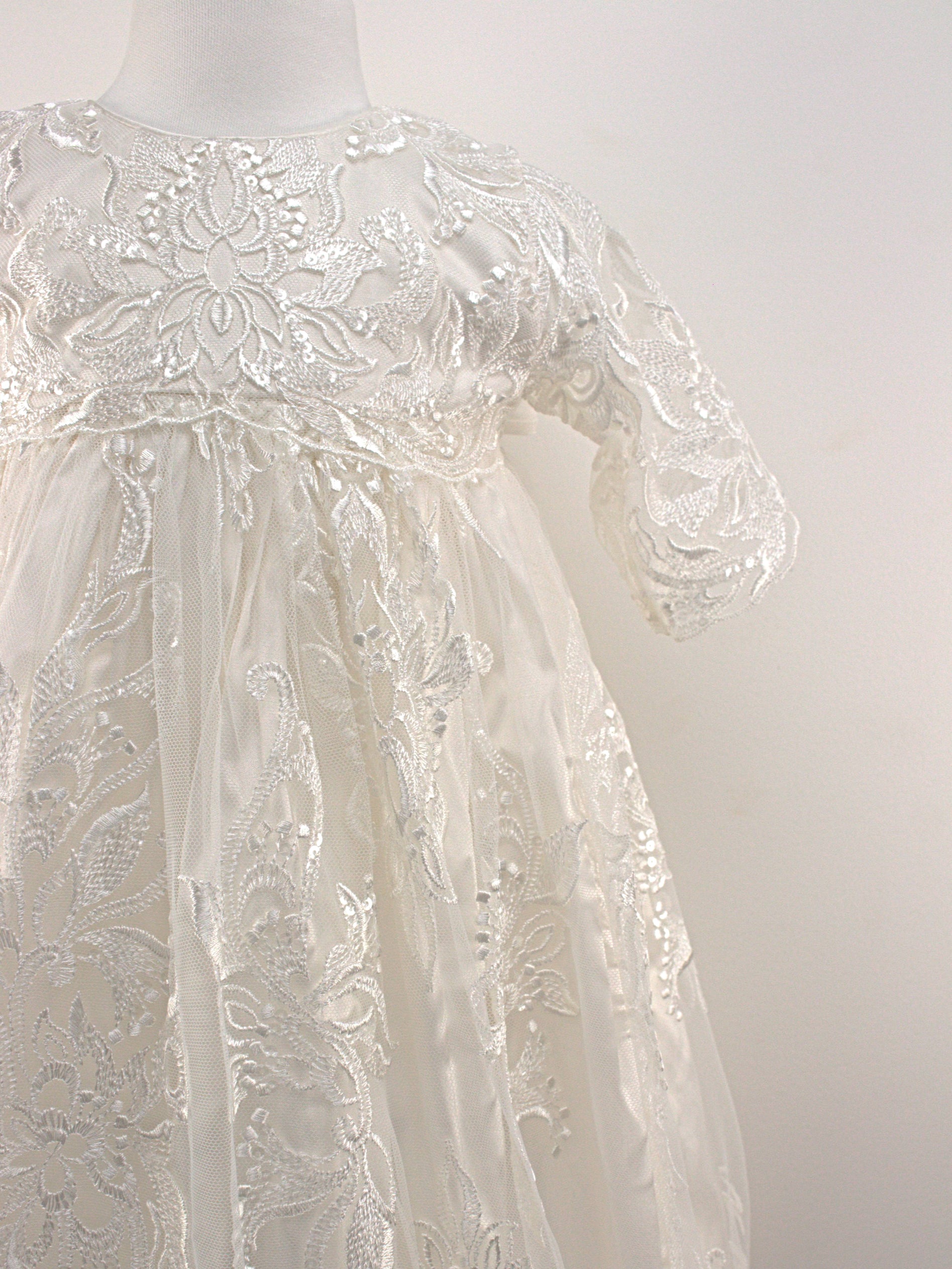 Close-up of the My Blessing Divine christening gown’s front bodice showing detailed floral lace and bead embroidery.