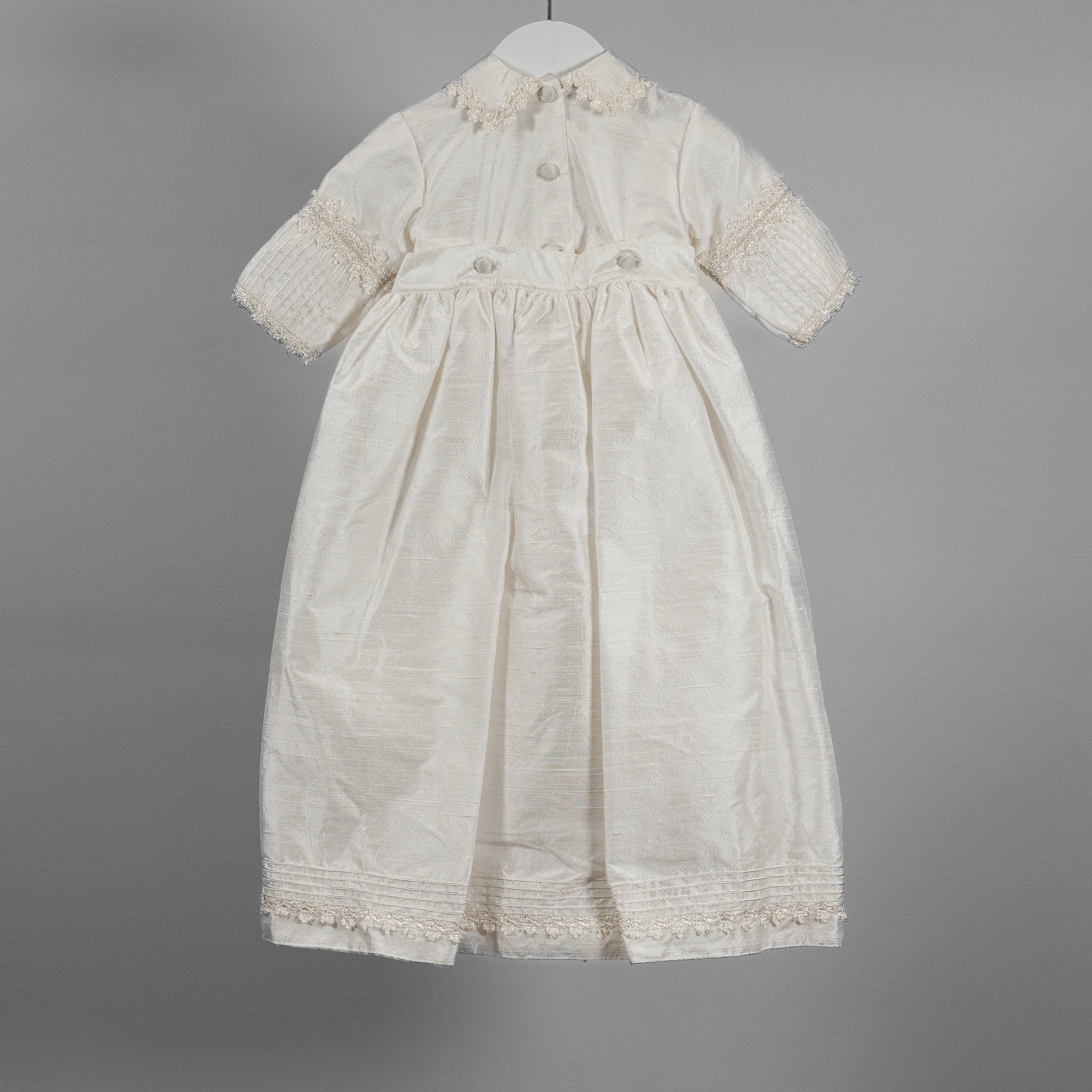 Back view of My Blessing ivory Ezra Dupioni silk baptism romper featuring a softly draped bib panel with elegant shuttle lace detailing.