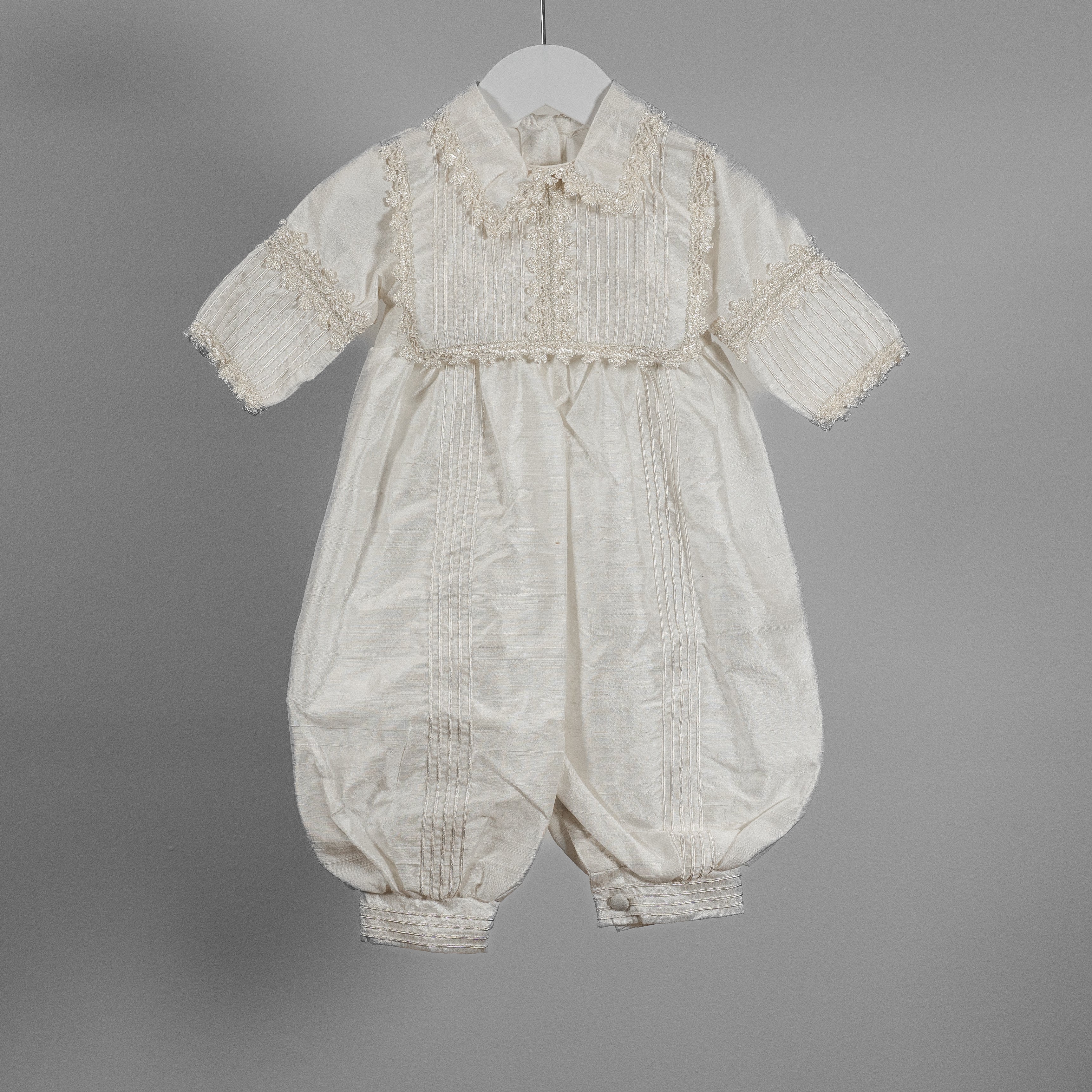 Front close-up of the My Blessing Dupioni Ezra silk romper showing the delicate shuttle lace trimming across the bib and collar.