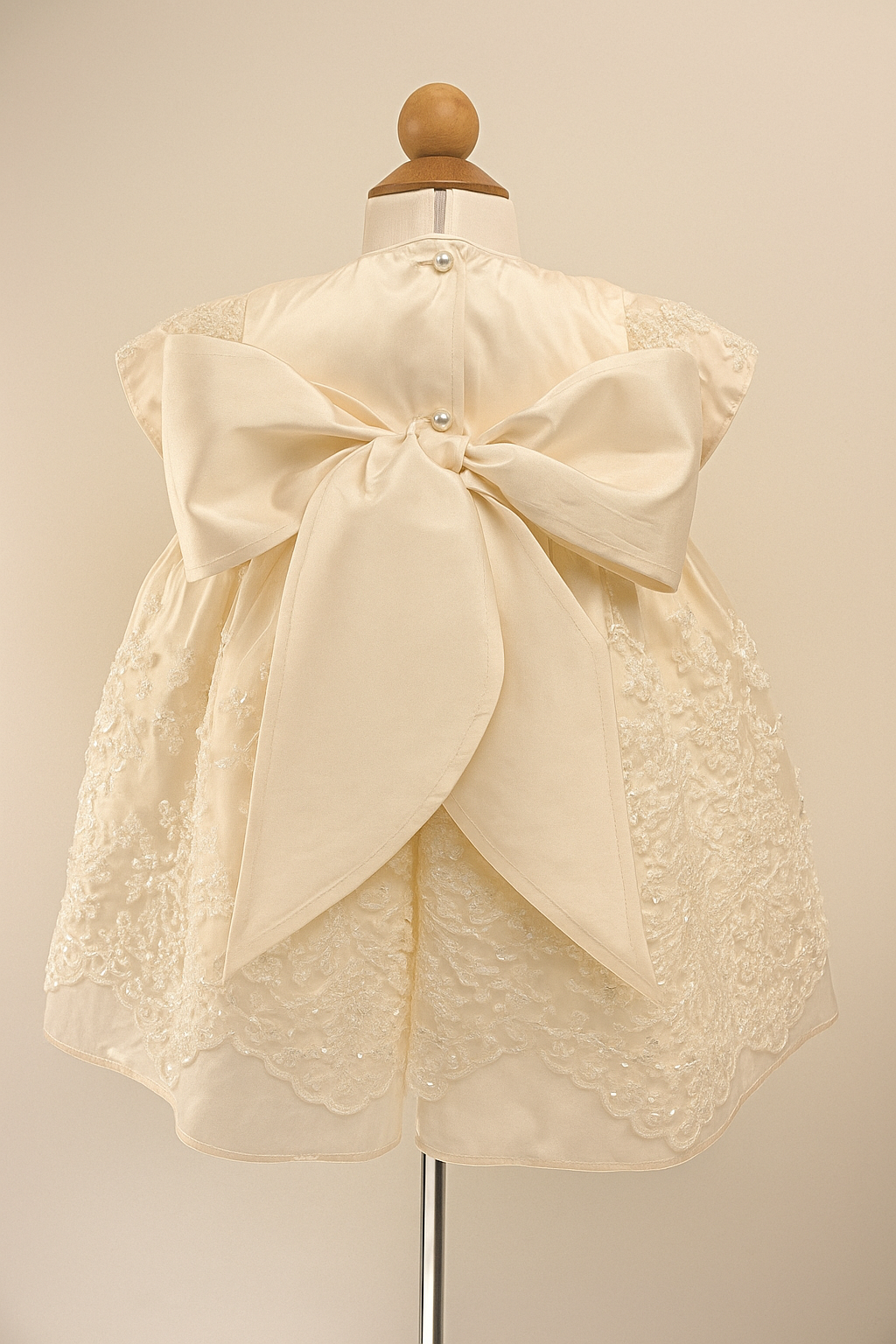 Back view of the My Blessing Fruitful ivory christening dress showing embroidered lace detailing, back button closure and large pure silk bow.