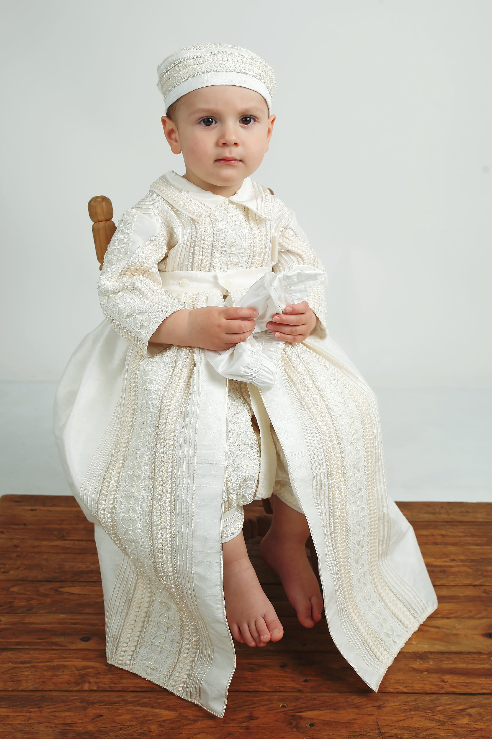 Baby boy posing in the My Blessing Gabriel Dupioni silk romper featuring hand‑finished pearl and lace detailing.
