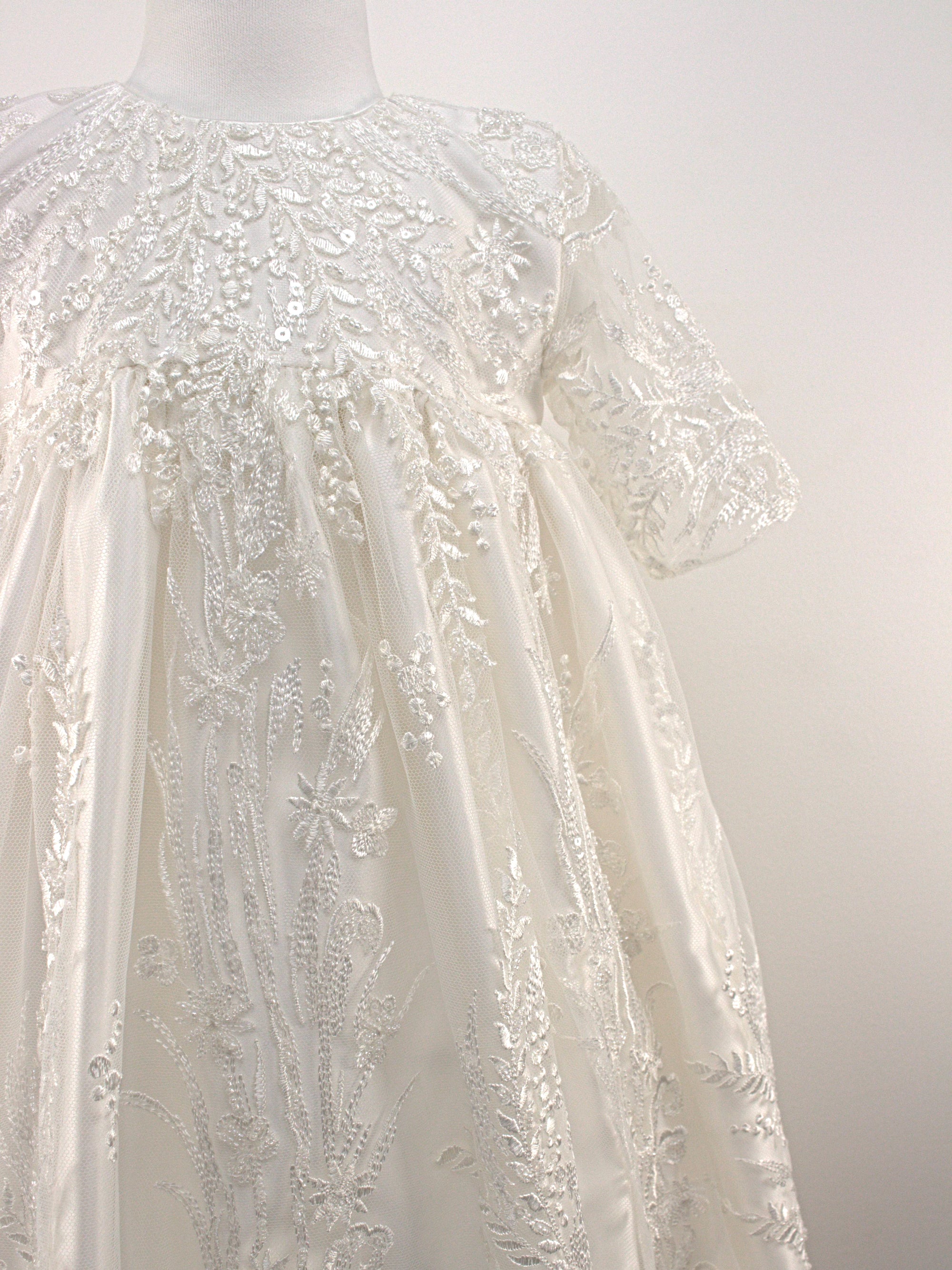 Close-up of the My Blessing Grateful christening gown’s front bodice showing detailed floral lace and bead embroidery.