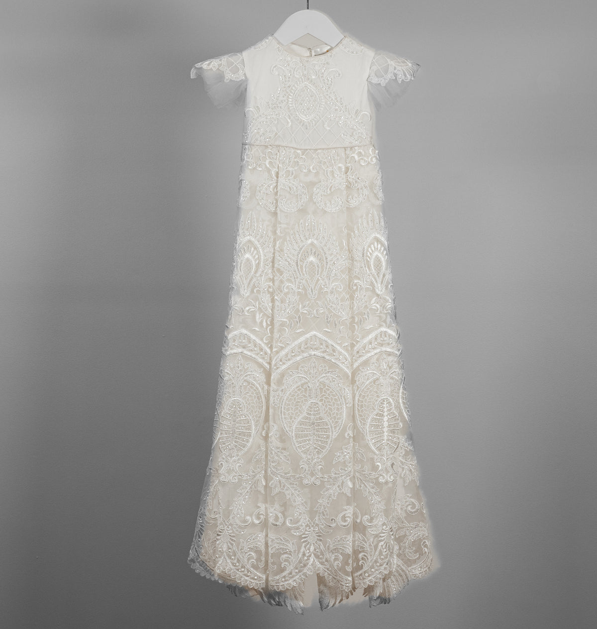 My Blessing ivory christening gown from the Lilly set featuring an embroidered lace bodice, elegant sleeves, and a flowing cotton‑underlay skirt.