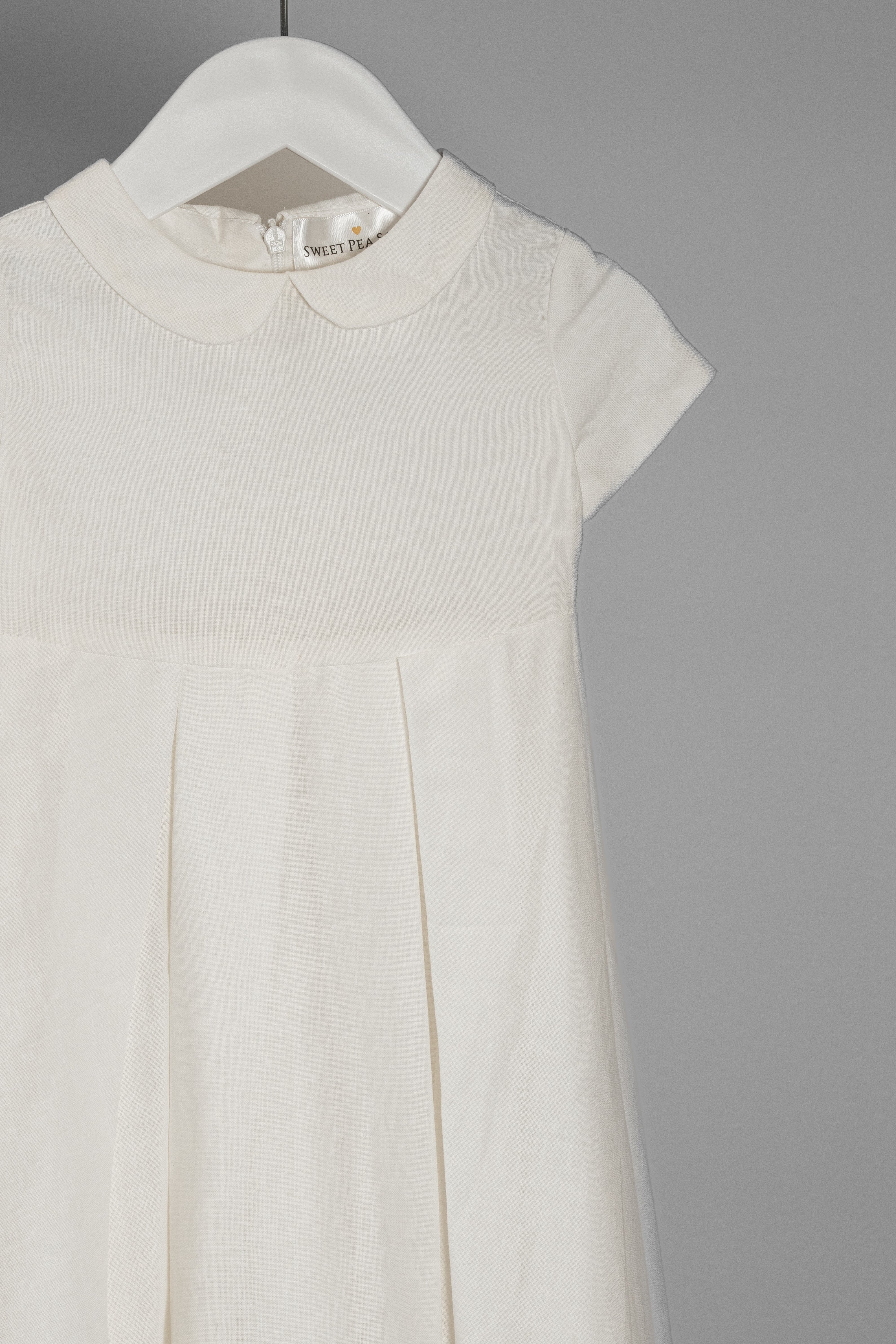 Close-up of the My Blessing Noa christening gown showing the linen texture, Peter Pan collar, and clean front pleat detailing.