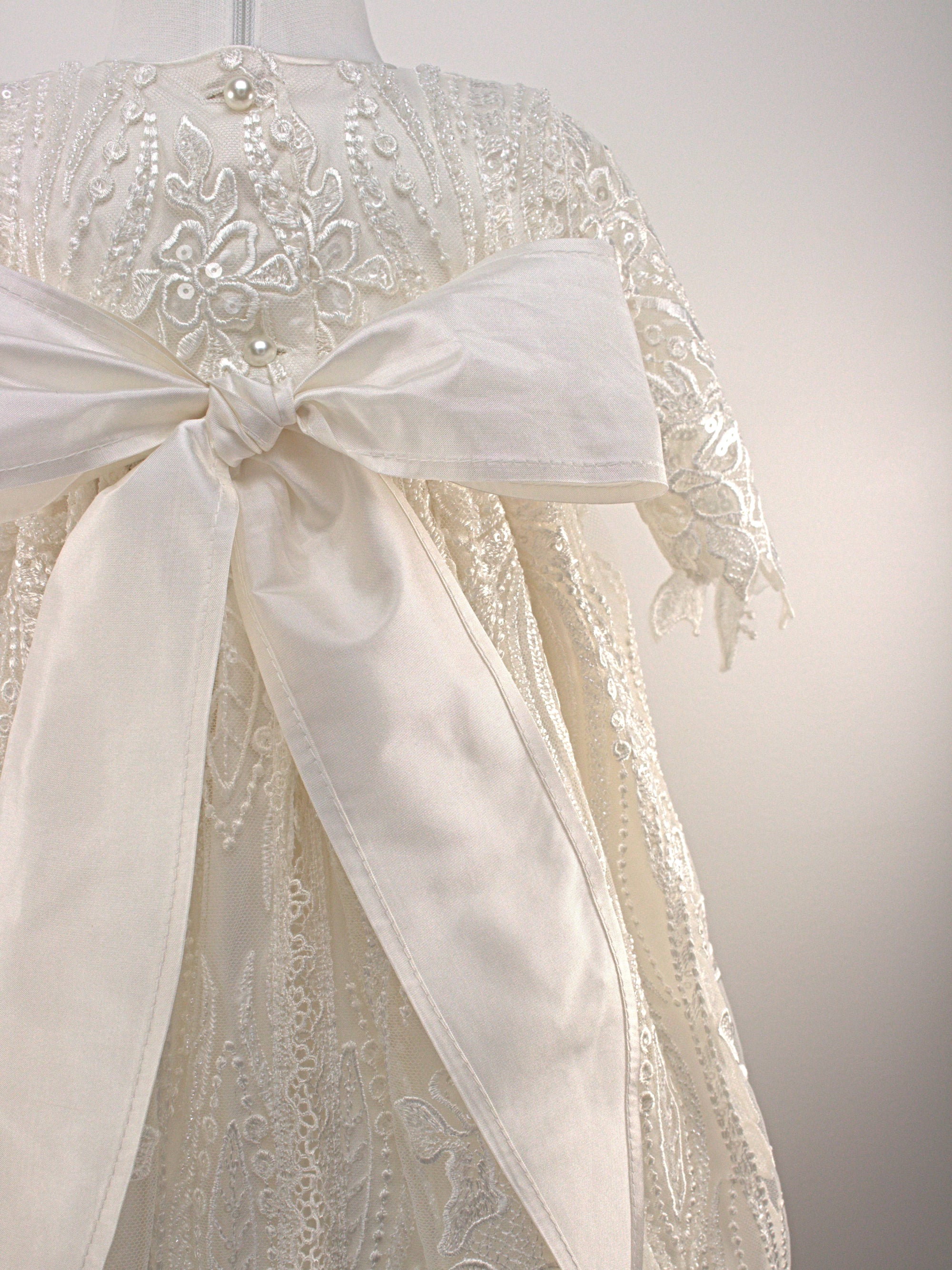 Close-up of My Blessing Praise ivory christening gown’s back bodice featuring delicate lace patterns and button or tie closures.