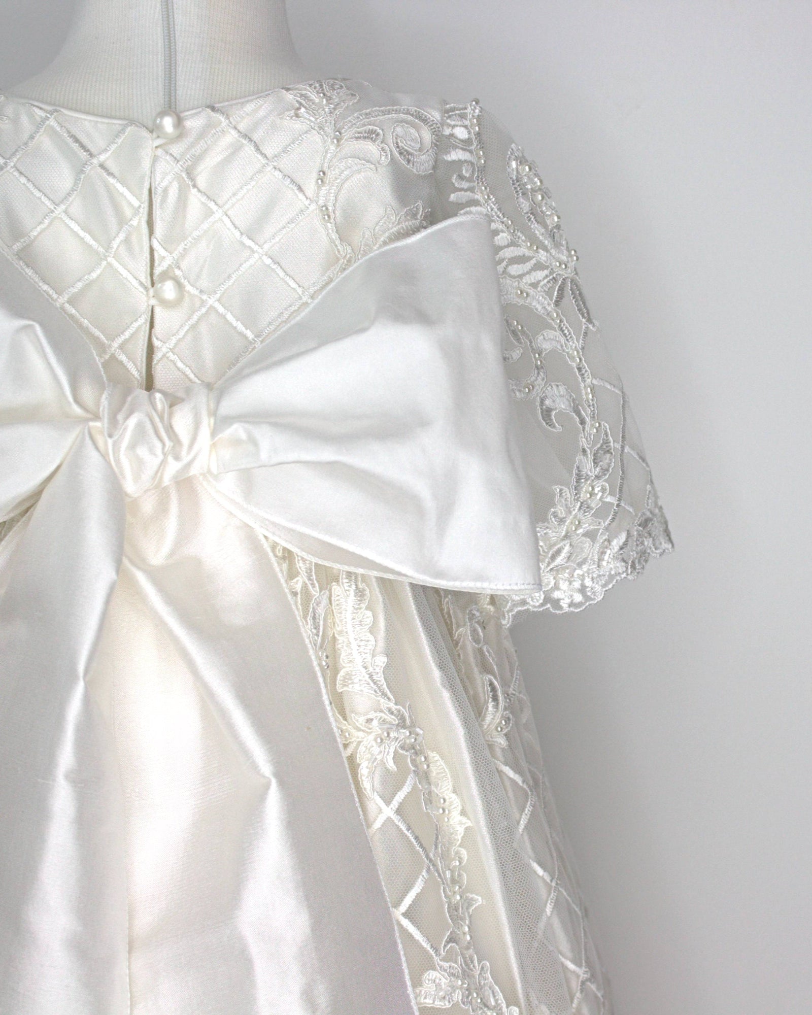 Close-up of the My Blessing Psalms gown’s back bodice featuring delicate lace patterns decorated with glass seed beads and pearl detailing.
