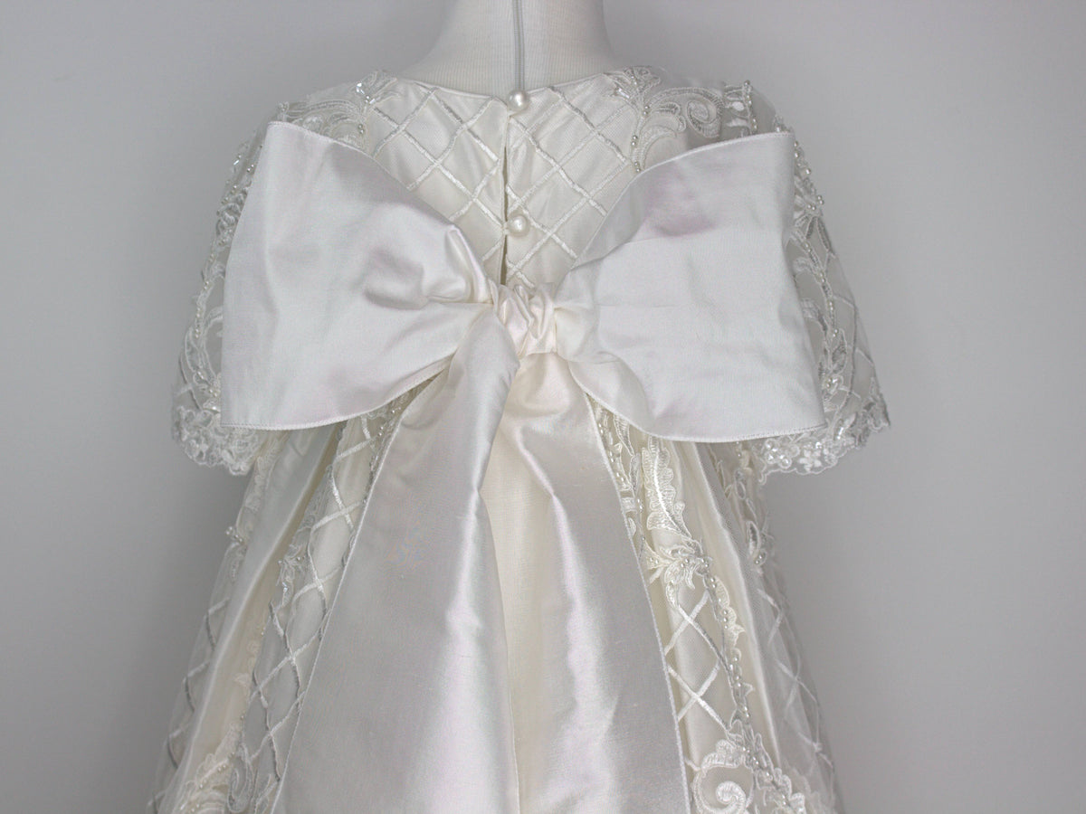Back view of the My Blessing Psalms gown’s lace skirt showcasing soft movement and subtle shimmer from glass seed beads and pearls. This gown features a large pure silk bow.