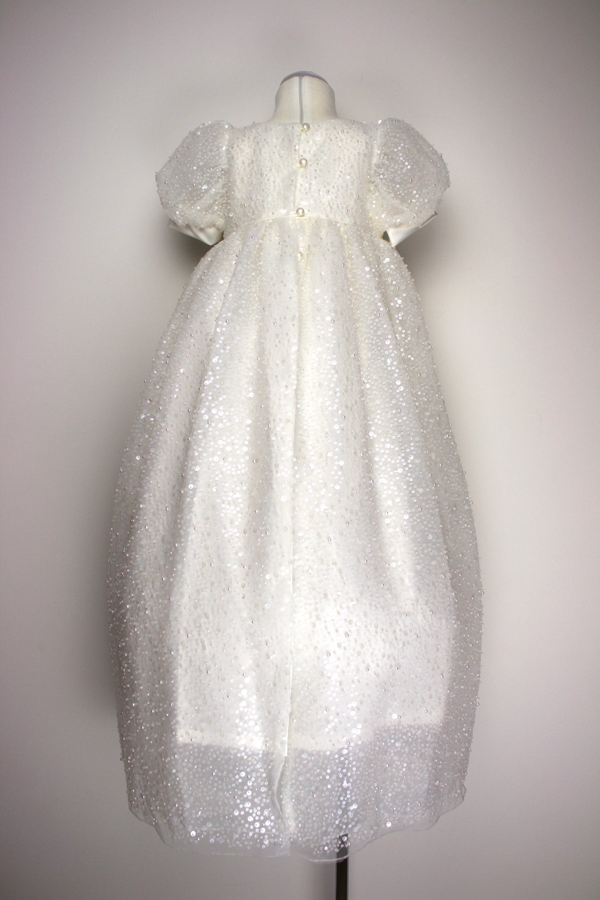 Back view of the My Blessing Ruth ivory christening dress showing lace detailing, back closures, and embellishments of sequins, glass seed beads, and miniature pearls.