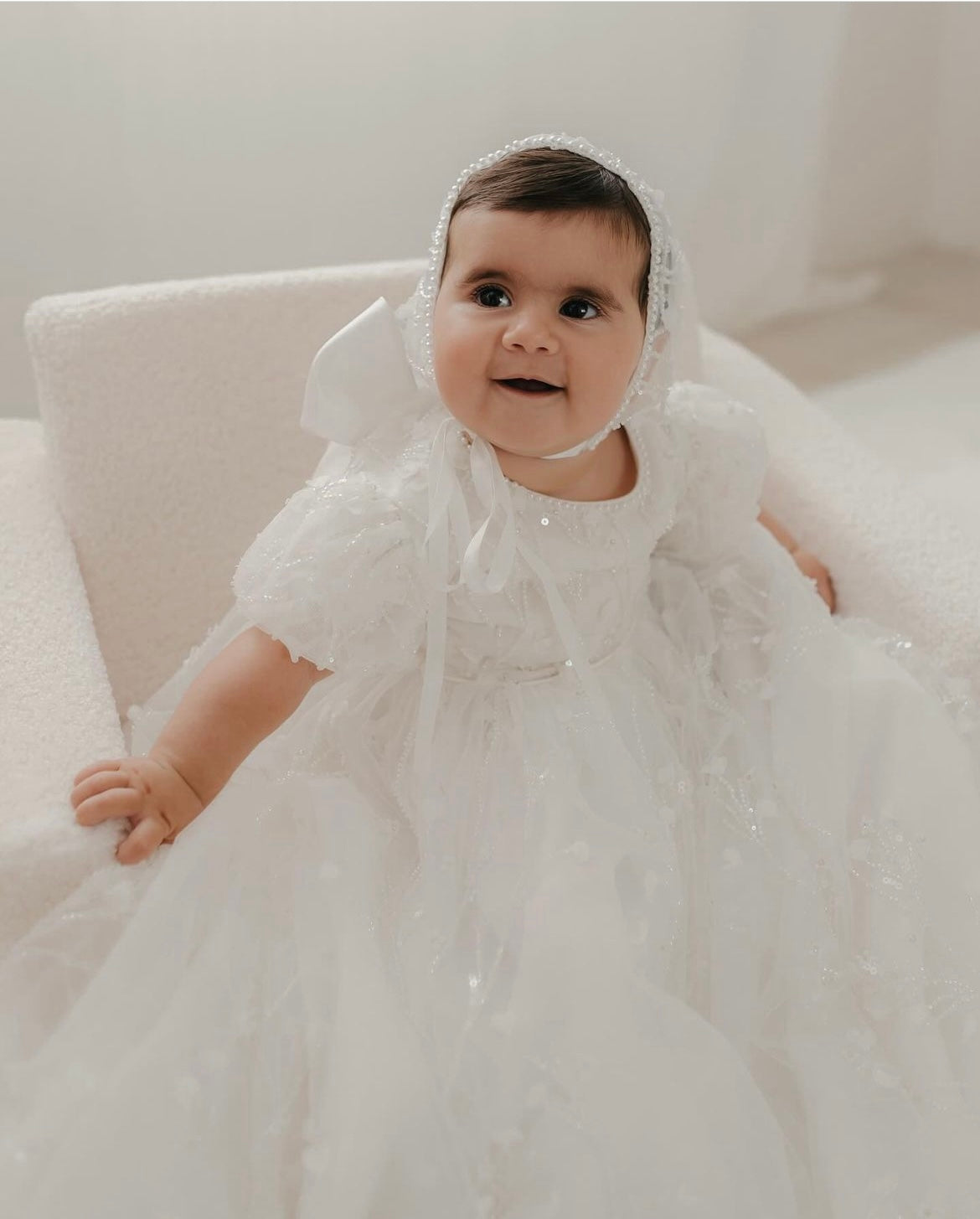 Front view of a baby wearing My Blessing Shamiran ivory christening gown, highlighting the floral lace bodice, beadwork, and full flowing satin skirt.