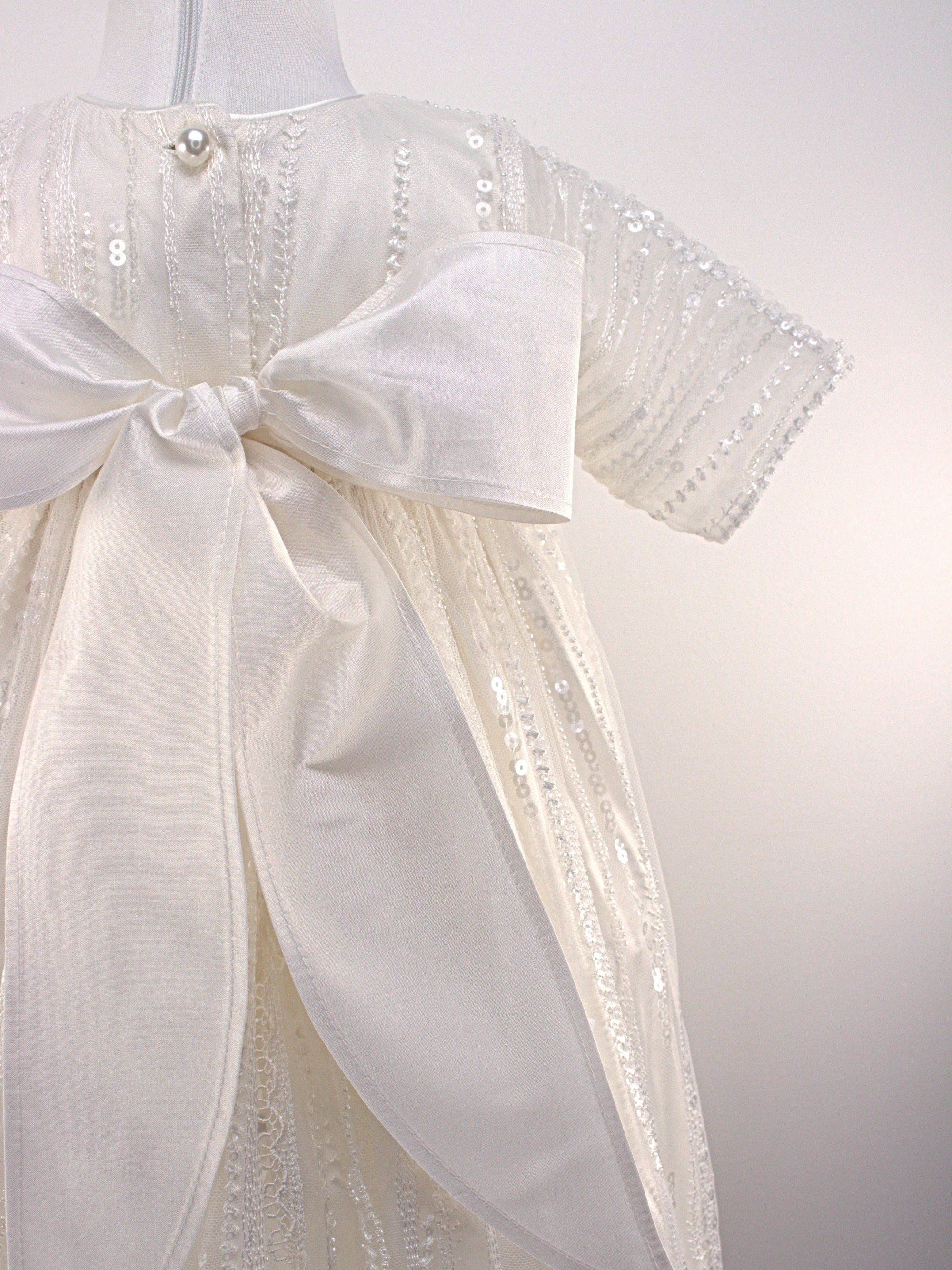 Close-up of My Blessing Soul christening gown's back bodice featuring delicate lace patterns and button or tie closures.