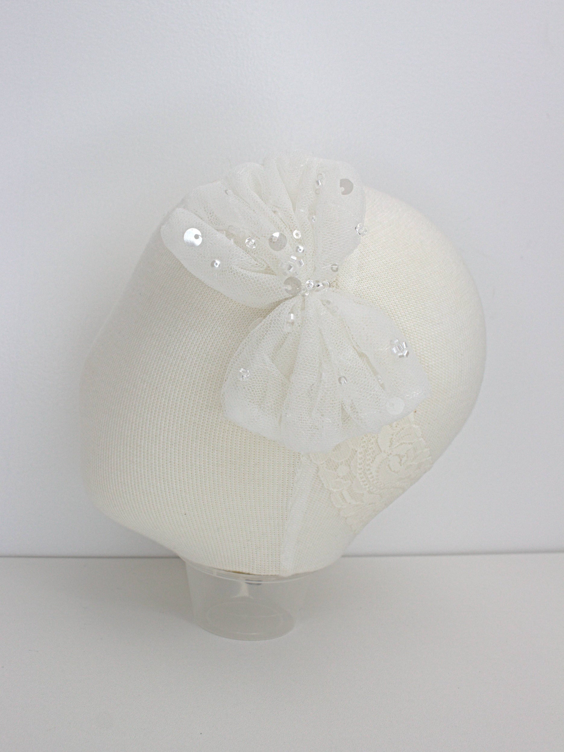 Ivory baby headband with a lace and bead embellishment and soft elastic band.