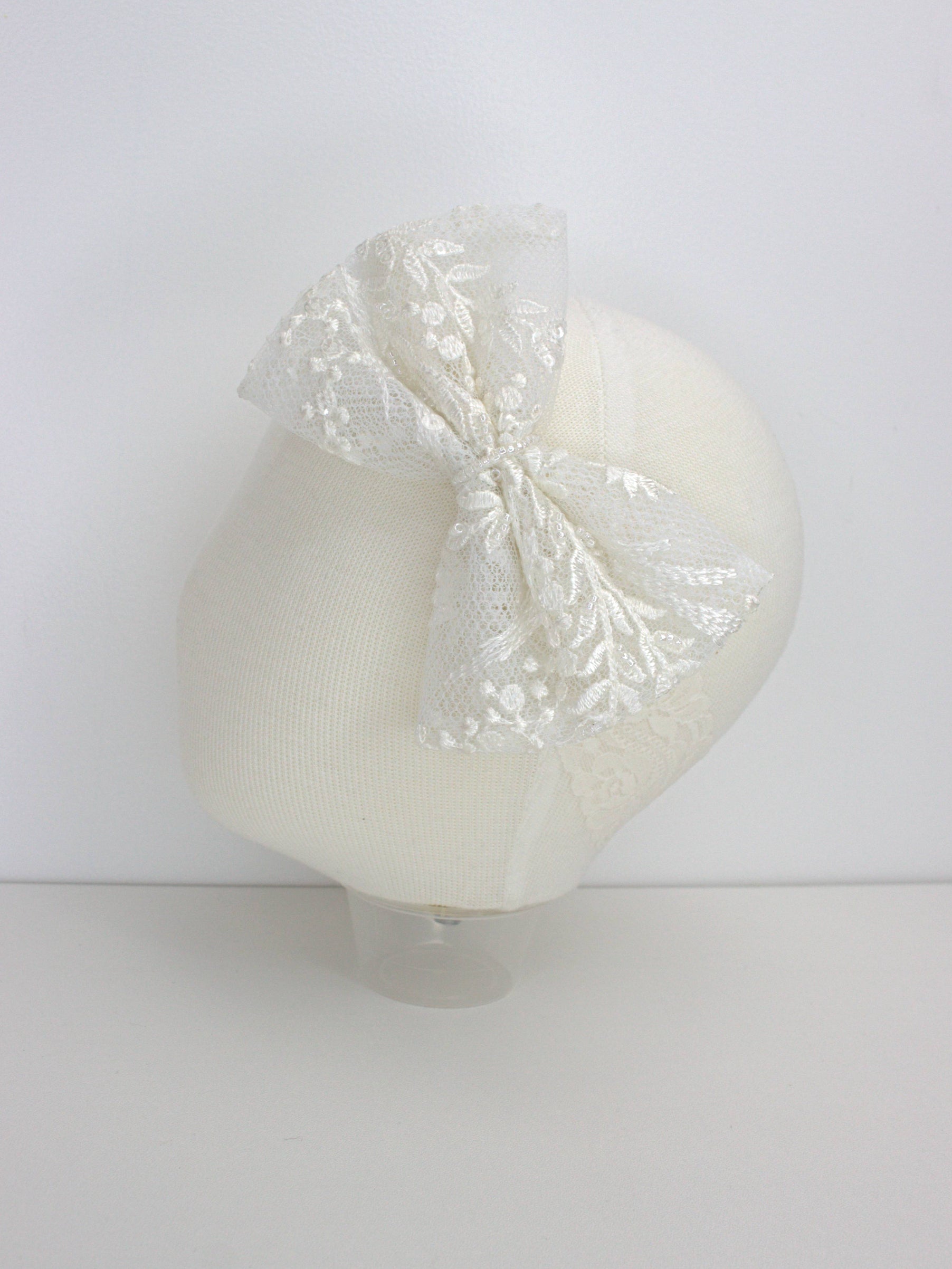 Ivory baby headband with a lace flower embellishment and soft elastic band for a comfortable fit.