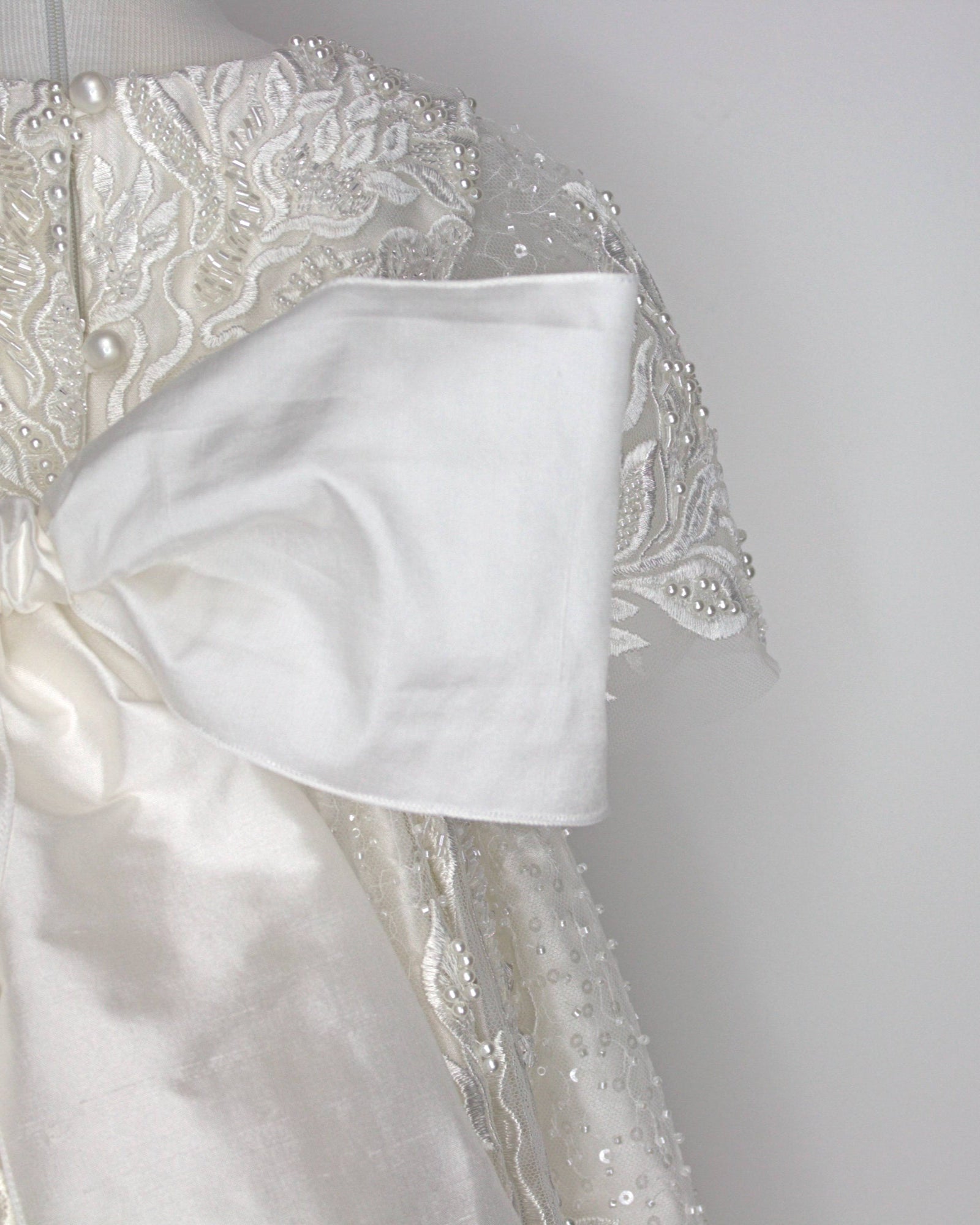 Back view of the My Blessing Zillah christening gown showing the flowing European lace overlay with shimmering Swarovski crystals, pearls, tubed glass beads and seed beads.