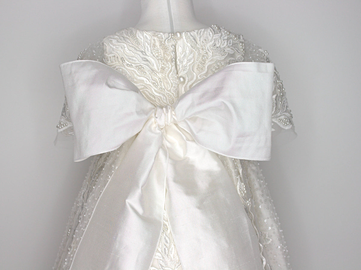 Back view of the My Blessing Zillah christening gown showing the flowing European lace overlay with shimmering Swarovski crystals, pearls, tubed glass beads, seed beads and an extra-large pure silk bow.