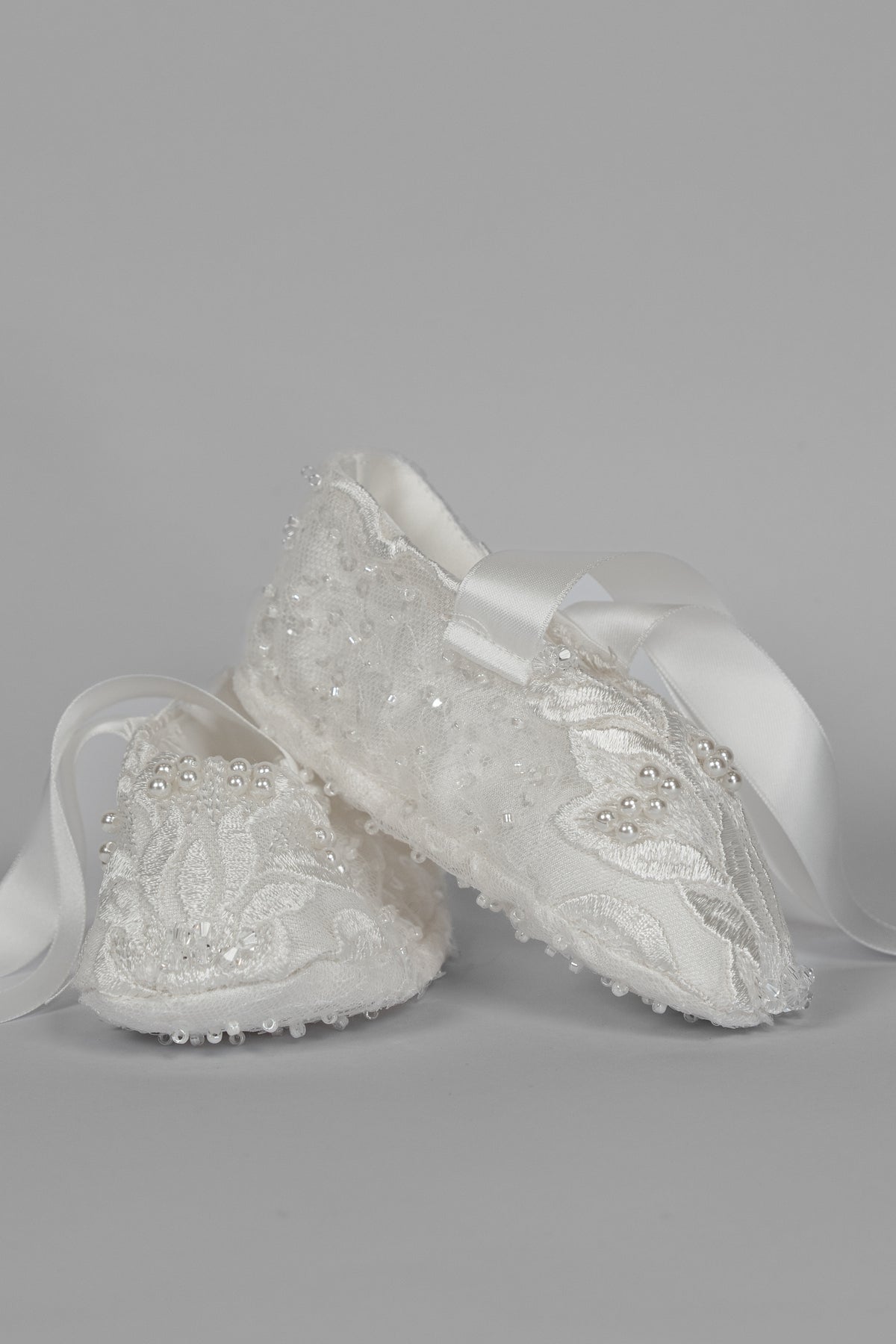 Ivory christening shoes from the My Blessing Zillah set featuring European bridal lace with intricate beadwork including Swarovski crystals, pearls, tubed glass beads and seed beads.