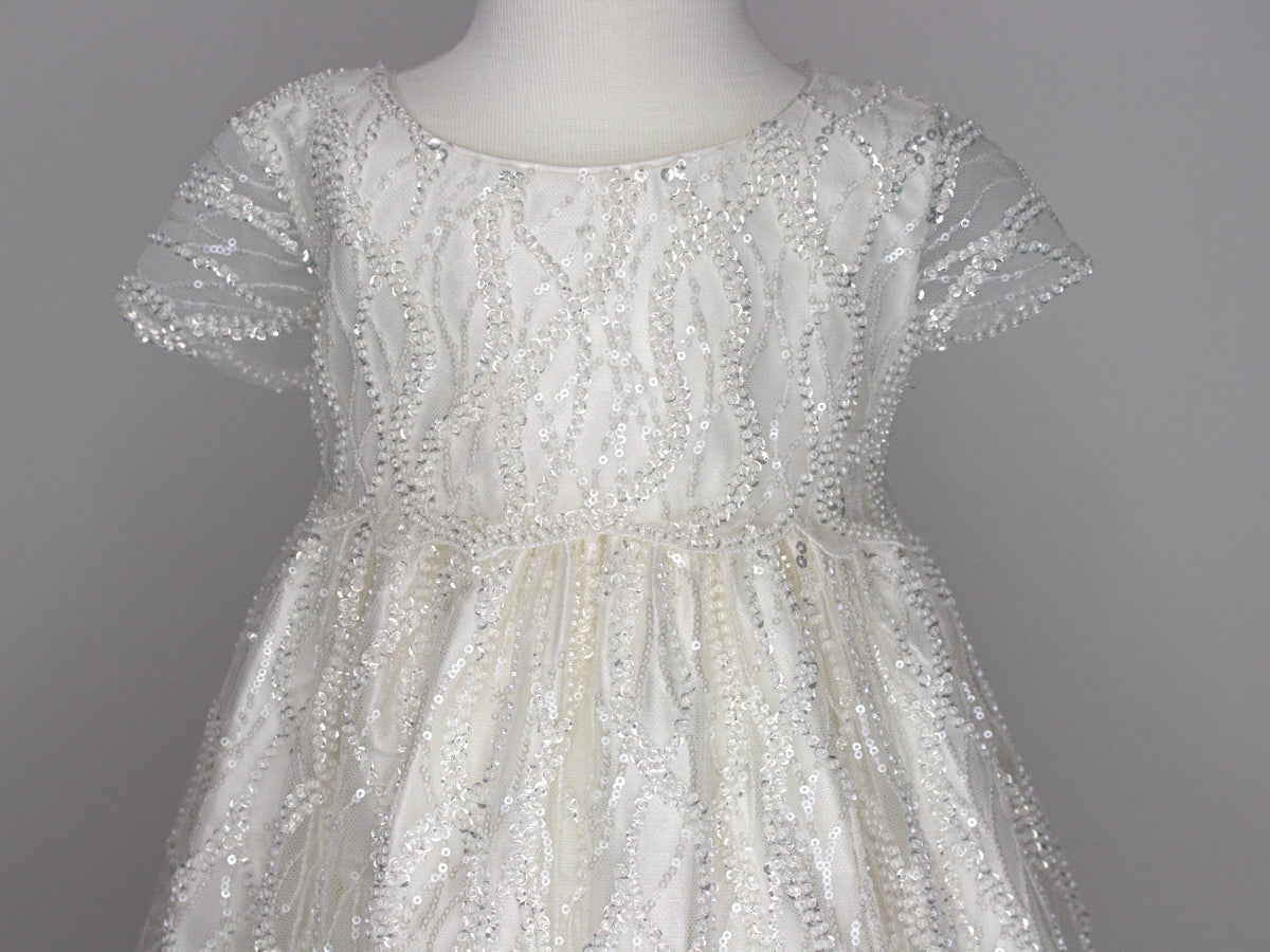 Close-up of the My Blessing Zuriel christening gown’s lace bodice showing hand‑embellished floral embroidery decorated with reflective sequins and glass seed beads.